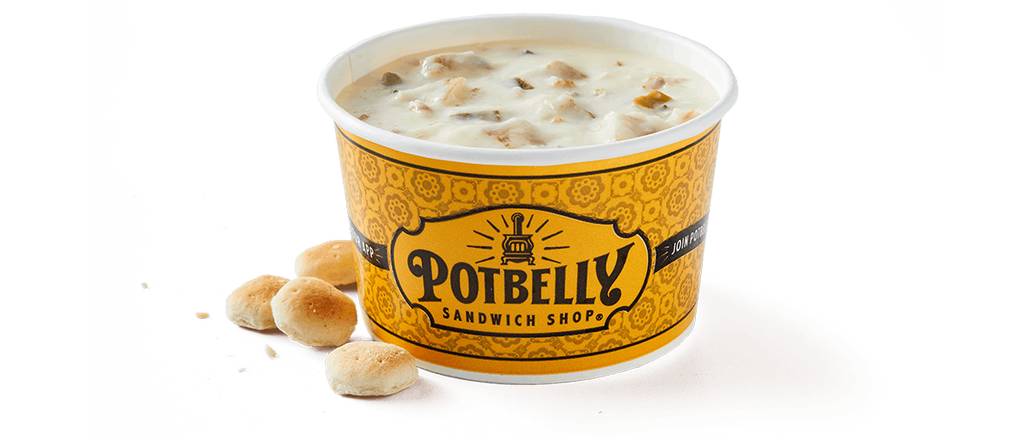 A cup of creamy soup with chunks, labeled “Potbelly Sandwich Shop,” sits beside several small round oyster crackers on a white background.