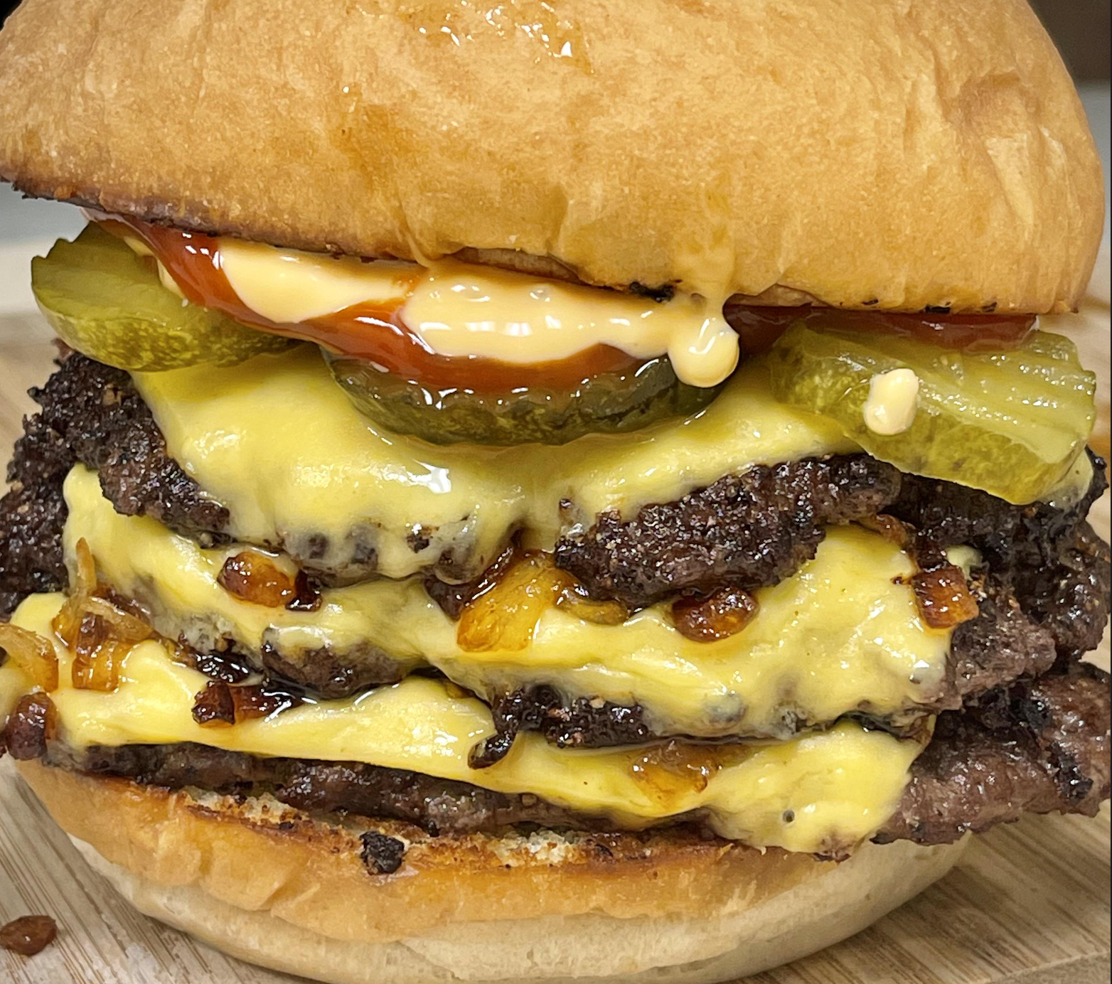 Close-up of a double cheeseburger with melted cheese, grilled beef patties, pickles, grilled onions, ketchup, and mayonnaise in a soft bun.