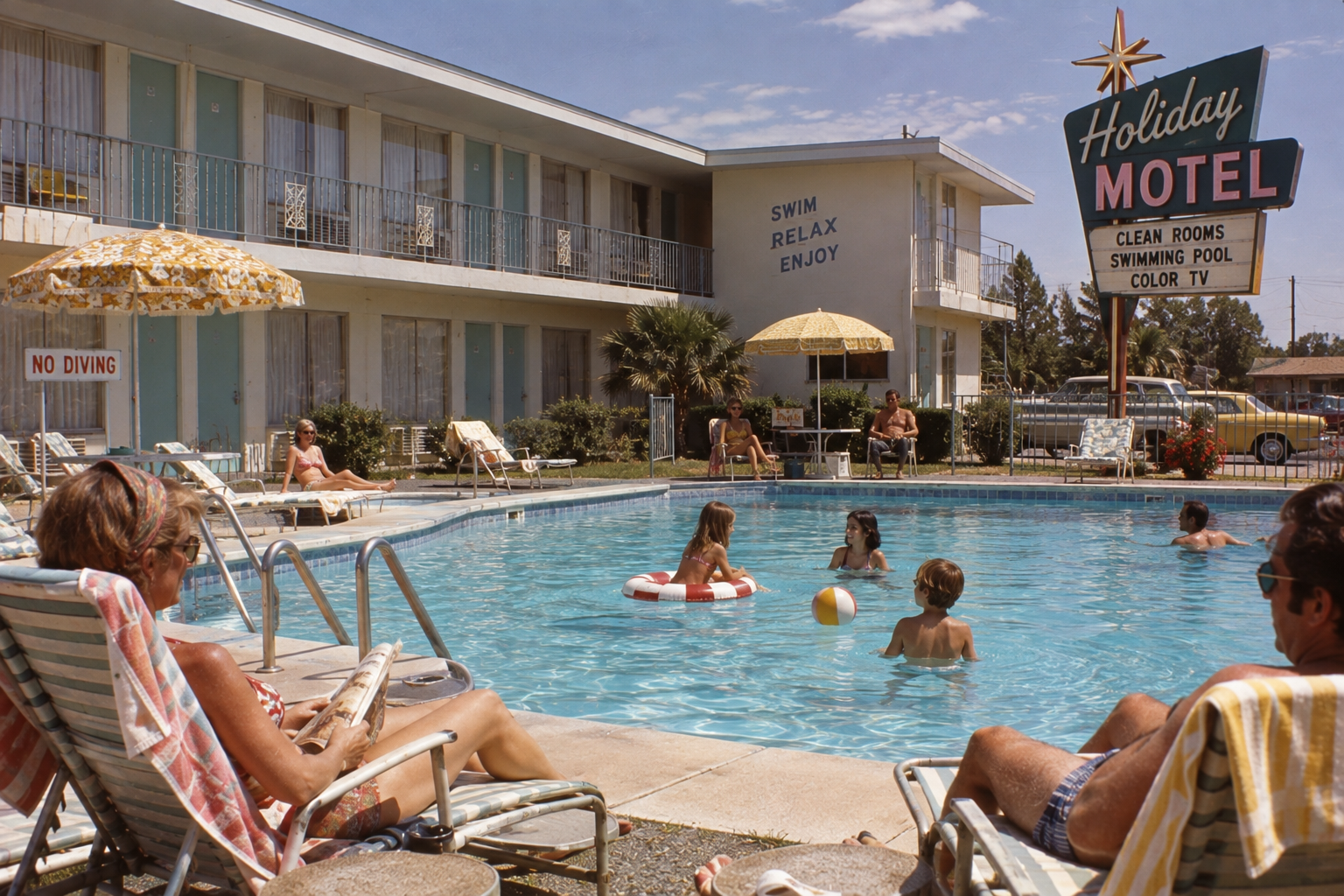 People relax poolside at a retro motel on a sunny day; kids swim and play in the water, while adults lounge under umbrellas. A large sign reads “Holiday Motel: Clean Rooms, Swimming Pool, Color TV.”