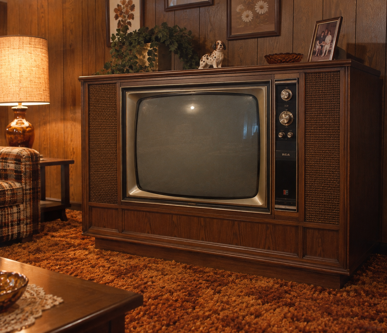 A vintage RCA console television sits on orange shag carpet in a retro living room with wood-paneled walls, plaid furniture, and old-fashioned decor items like a lamp, framed photos, and a ceramic dog. 1970s basement.
