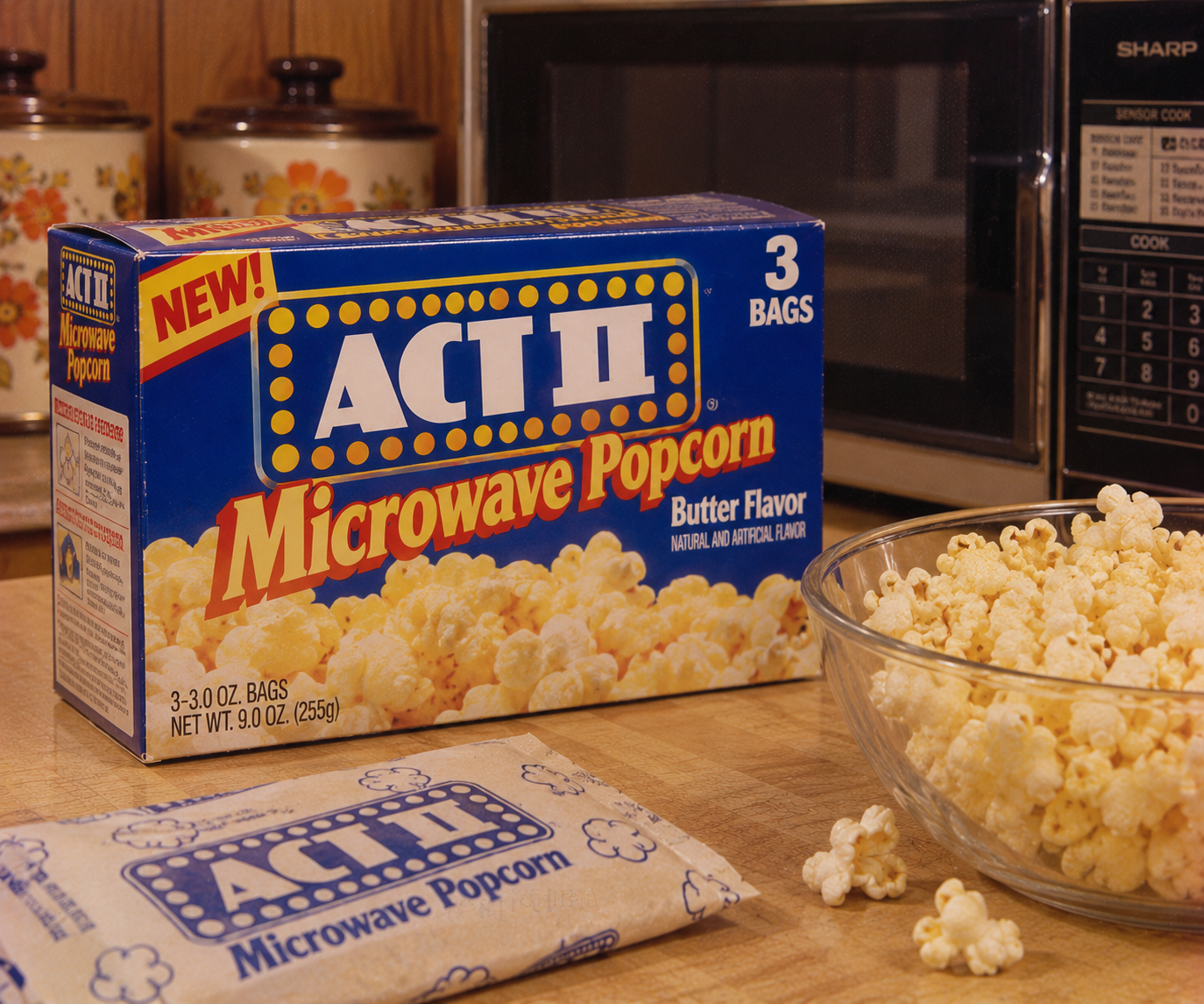 A box of ACT II Microwave Popcorn, a true 1980s grocery store staple, sits on a kitchen counter beside a bowl of popcorn, a microwave oven, and a sealed popcorn bag with ceramic containers in the background.