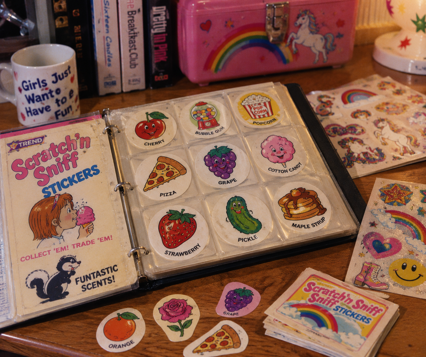 A binder of vintage scratch-and-sniff stickers is open on a wooden desk. Surrounding it are more stickers, a unicorn lunchbox, books, a lamp, and a mug that reads, “Girls Just Want to Have Fun.”