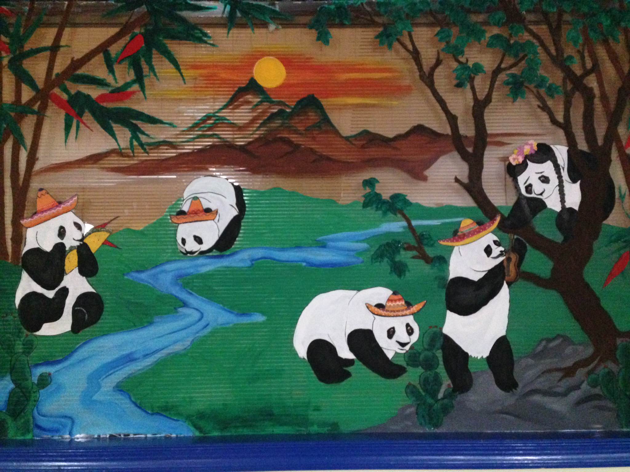 Five pandas wearing hats play and eat in a colorful landscape with bamboo, a river, mountains, and a setting sun in the background. One panda holds a flower, and another plays a flute.
