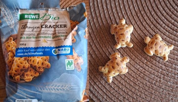 A bag of REWE Bio Laugen-Cracker turtle-shaped snacks on a woven mat, with three turtle-shaped crackers placed beside the package.