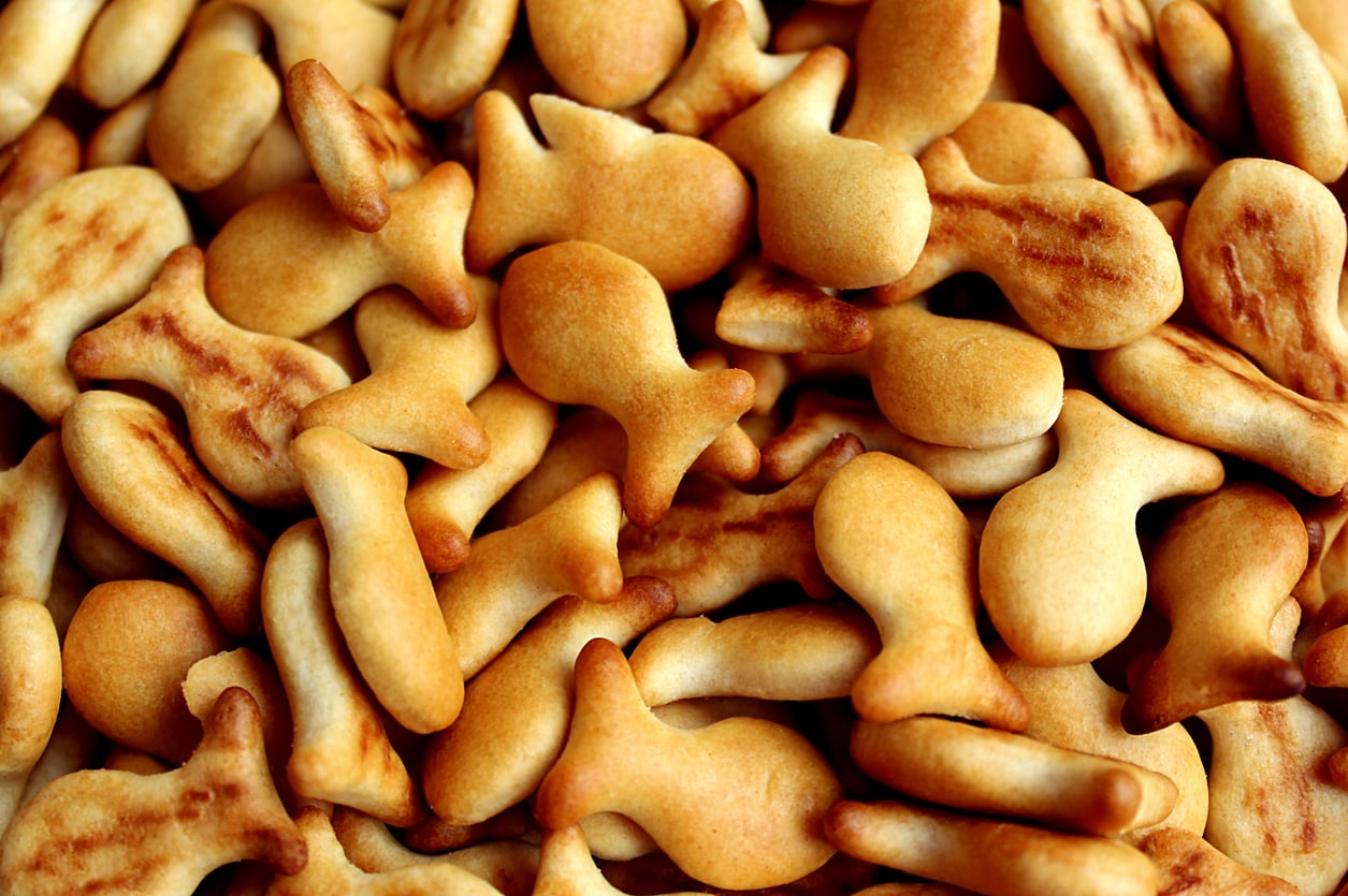 A close-up of many small, golden brown, fish-shaped crackers overlapping each other.