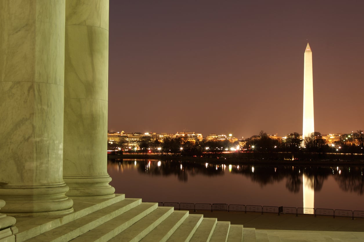 Marble steps at night with the illuminated Washington Monument and city lights reflecting on the water, seen from the Jefferson Memorial in Washington, D.C.