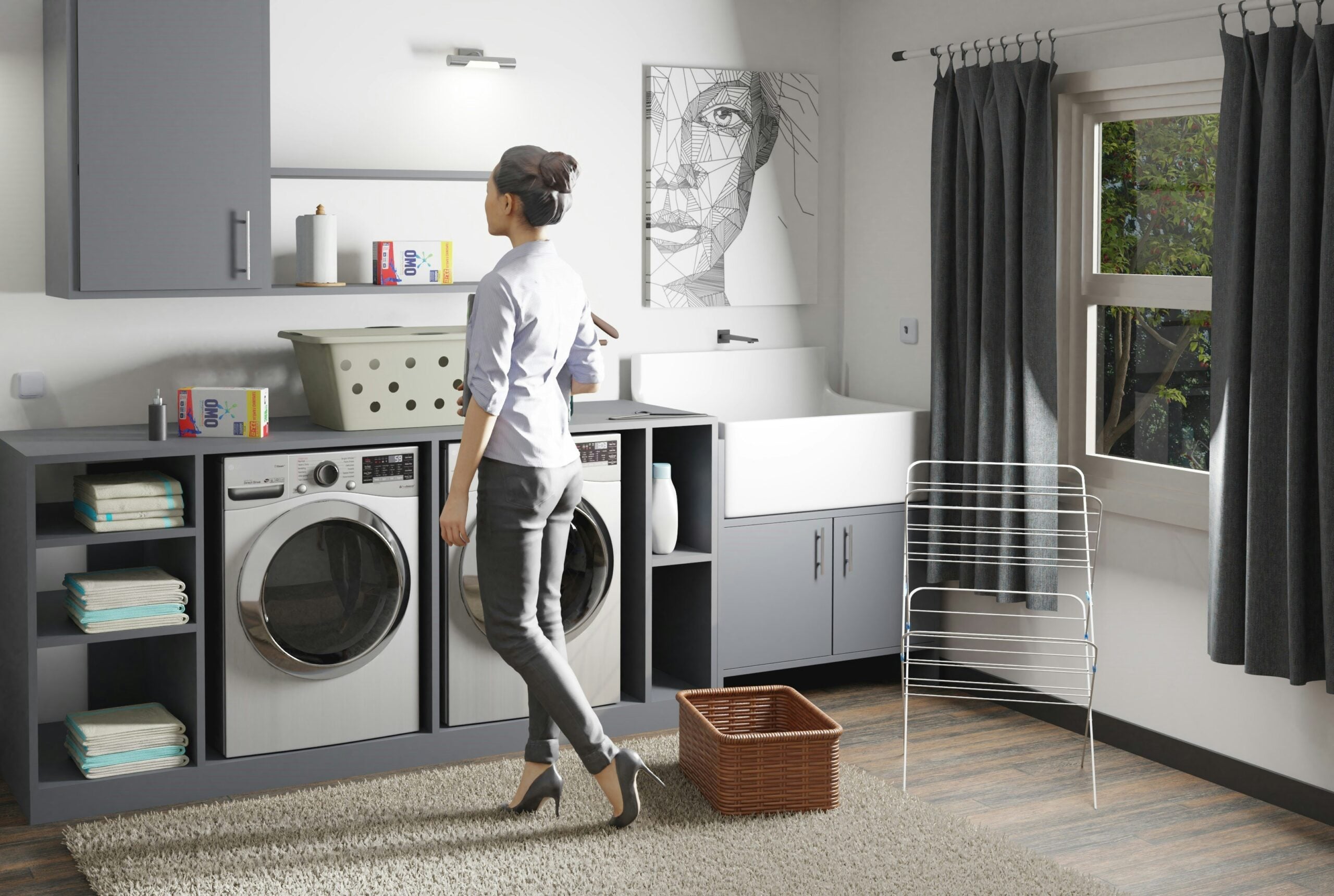 A woman stands in a modern laundry room, facing a washing machine and dryer. She holds a laundry basket. There are shelves with towels, detergent on the counter, a drying rack, window with curtains, and framed artwork on the wall.