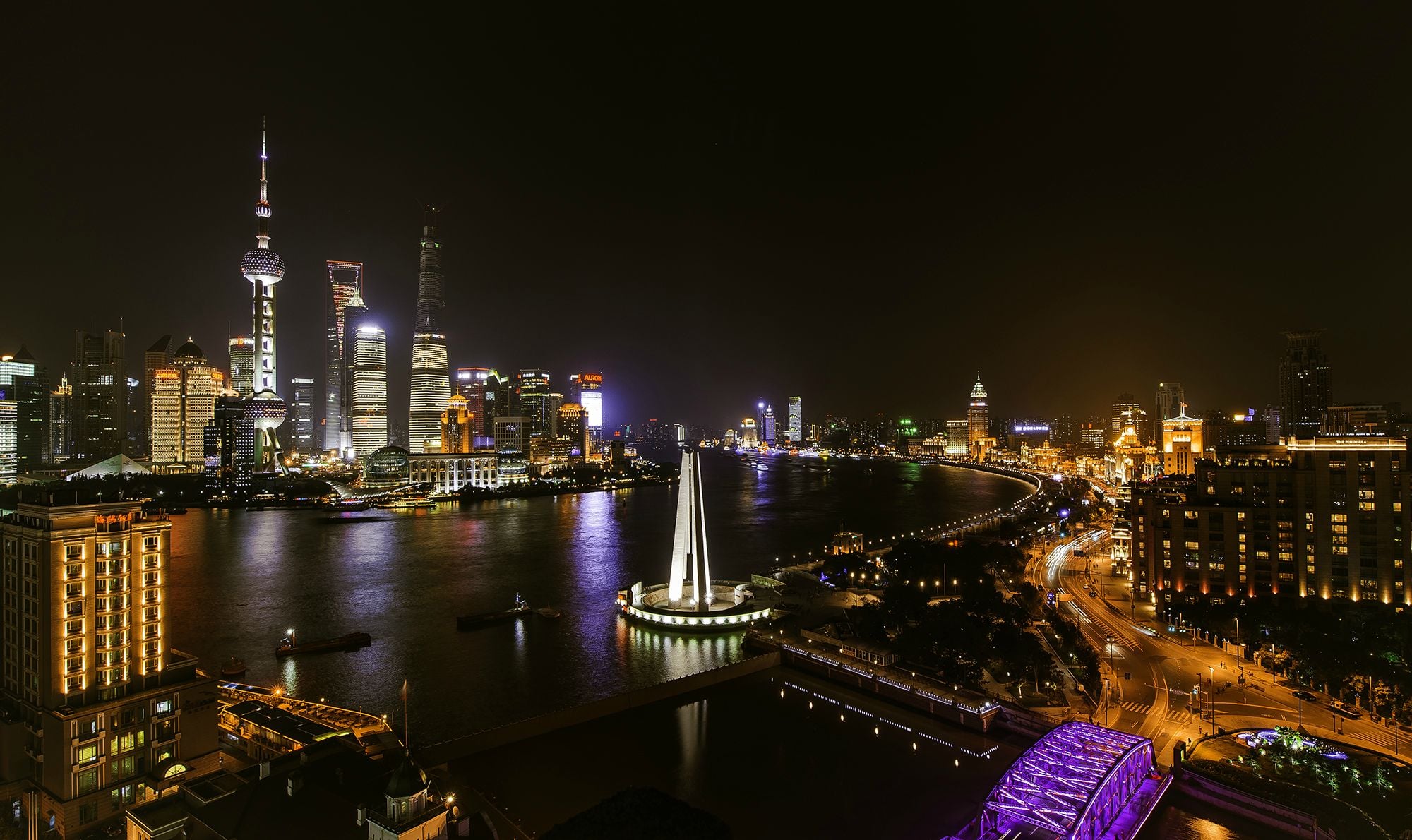 Shanghai skyline at night with illuminated skyscrapers, the Oriental Pearl Tower, and bright city lights reflecting on the Huangpu River—a breathtaking sight in one of the Biggest Cities In The World.