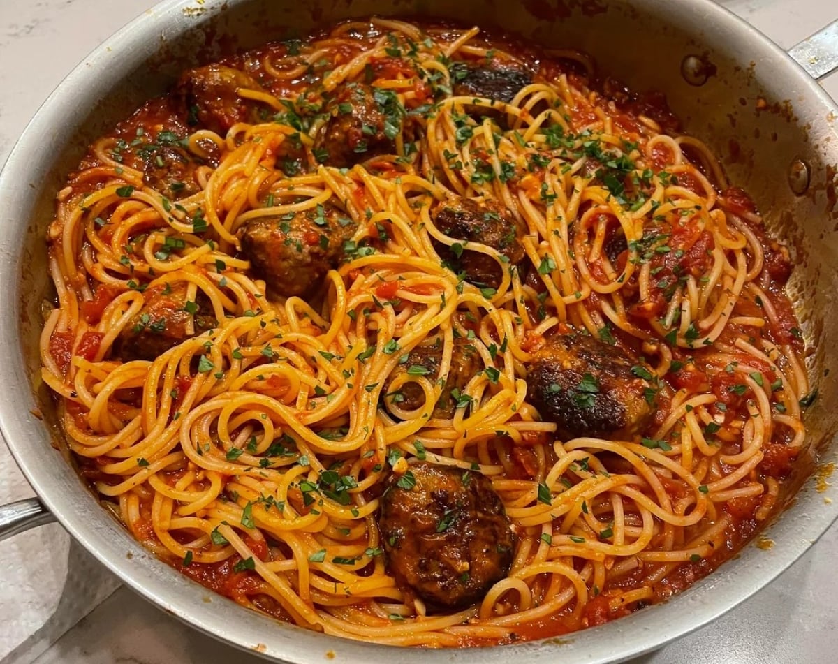 A pan filled with spaghetti and tomato sauce, topped with meatballs and garnished with chopped parsley—perfect for those seeking inspiration from mouthwatering photos of pasta.