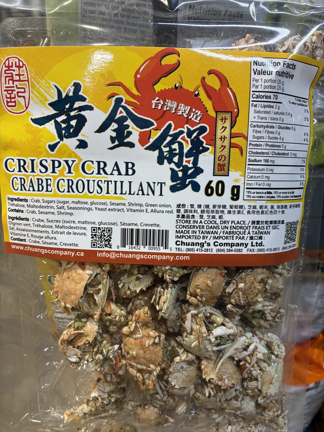 A clear bag of Crispy Crab snack showing dried crab pieces inside. The yellow label has images of red crabs, nutritional facts, and text in English, Chinese, and Japanese. Net weight is 60g.