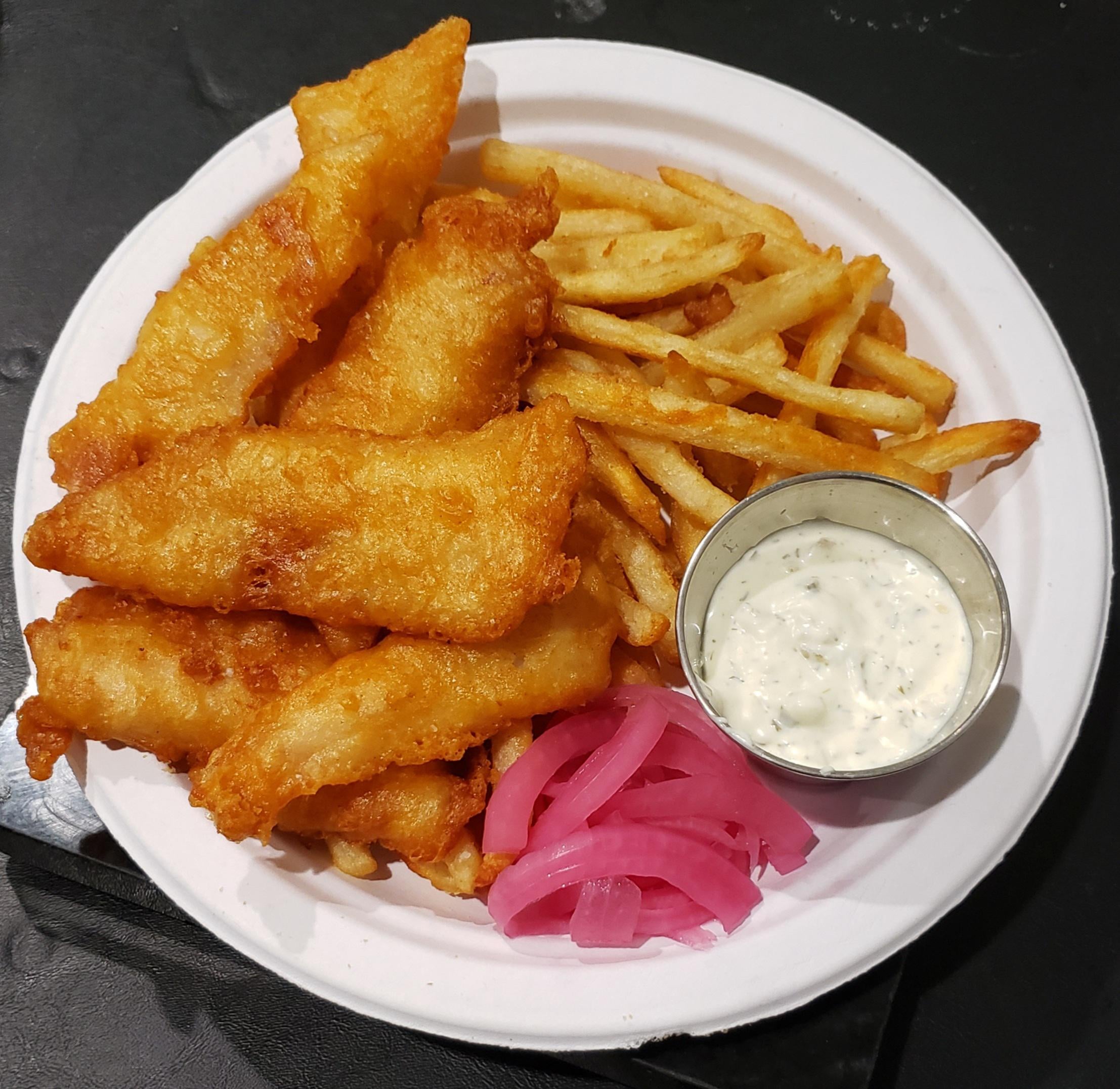 A plate of golden fried fish fillets with crispy fries, a serving of pickled red onions, and a small cup of tartar sauce on the side.