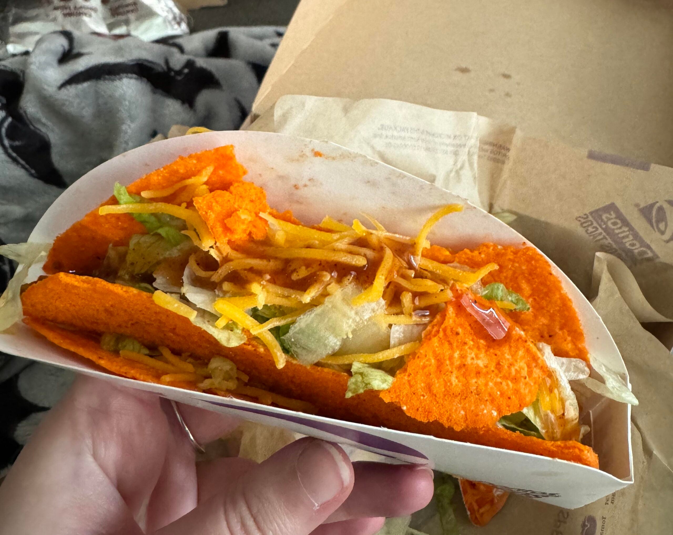 A Doritos Locos taco in a paper sleeve, held in a hand.