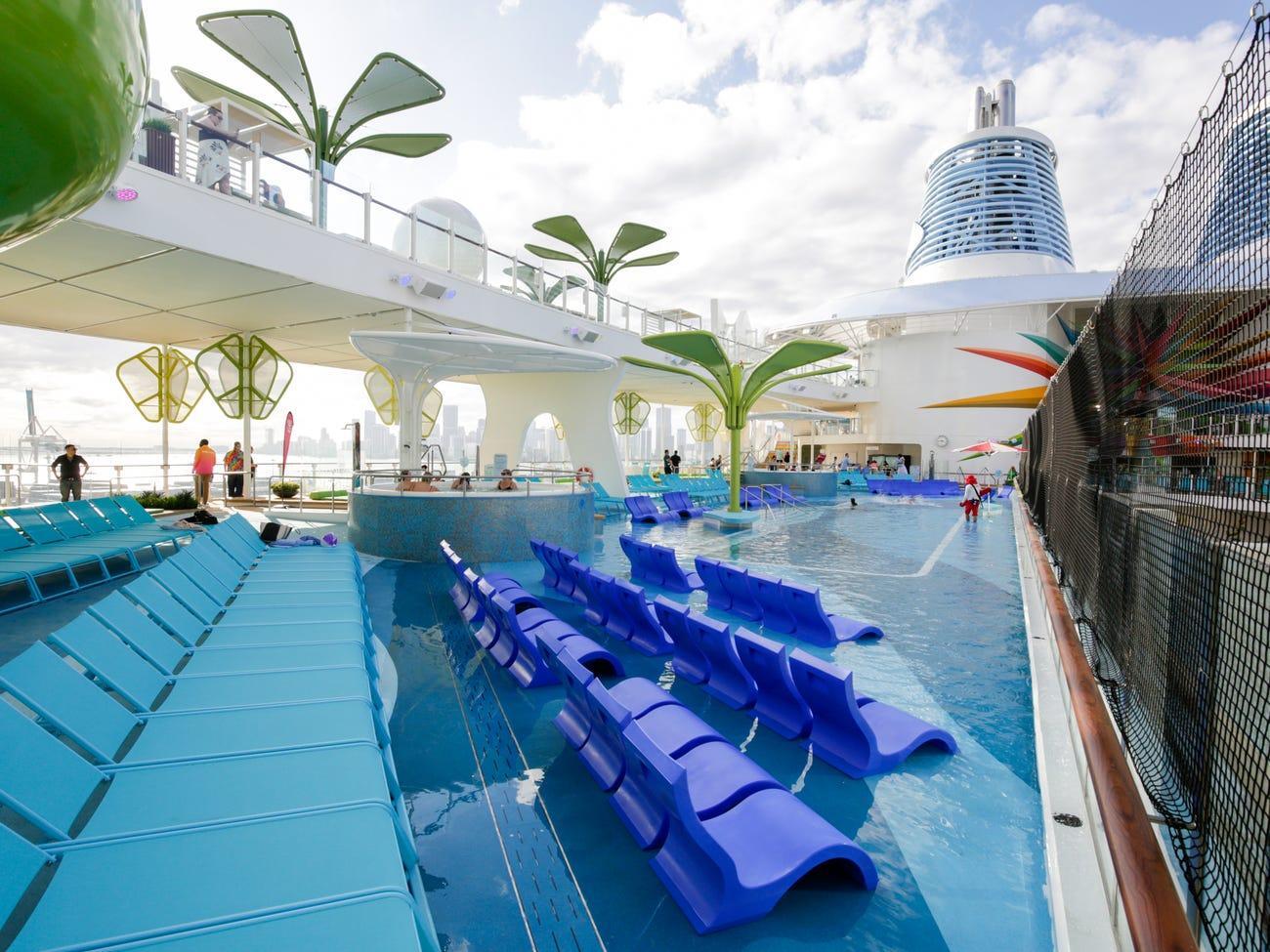 Blue lounge chairs partially submerged in the shallow water of a cruise ship pool deck.