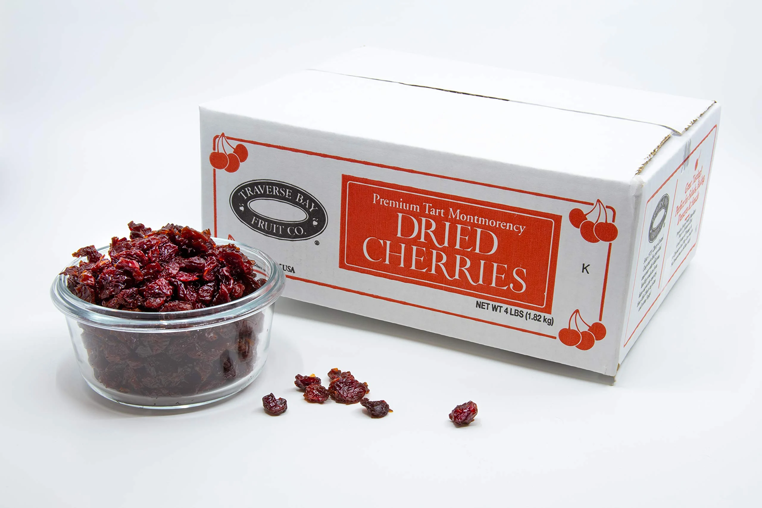 A glass bowl filled with dried tart cherries next to a bulk box labeled Traverse Bay Fruit Co. Premium Tart Montmorency Dried Cherries, making for the best souvenir.