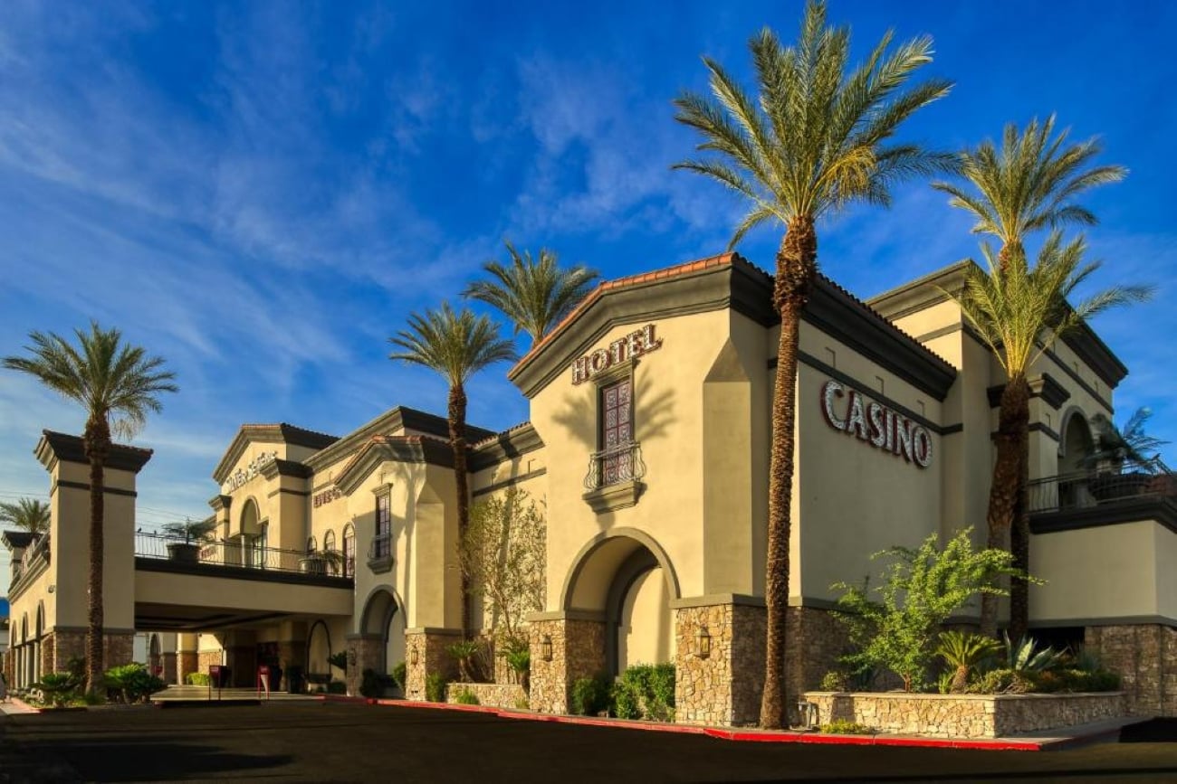 A beige hotel and casino building with palm trees and a clear blue sky.