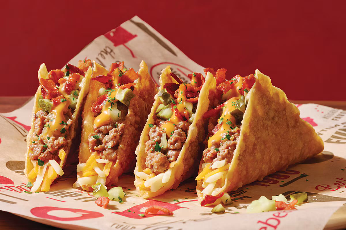 Things $50 buys: Four tacos in fried shells topped with ground meat, shredded cheese, diced pickles, bacon, and sauce.