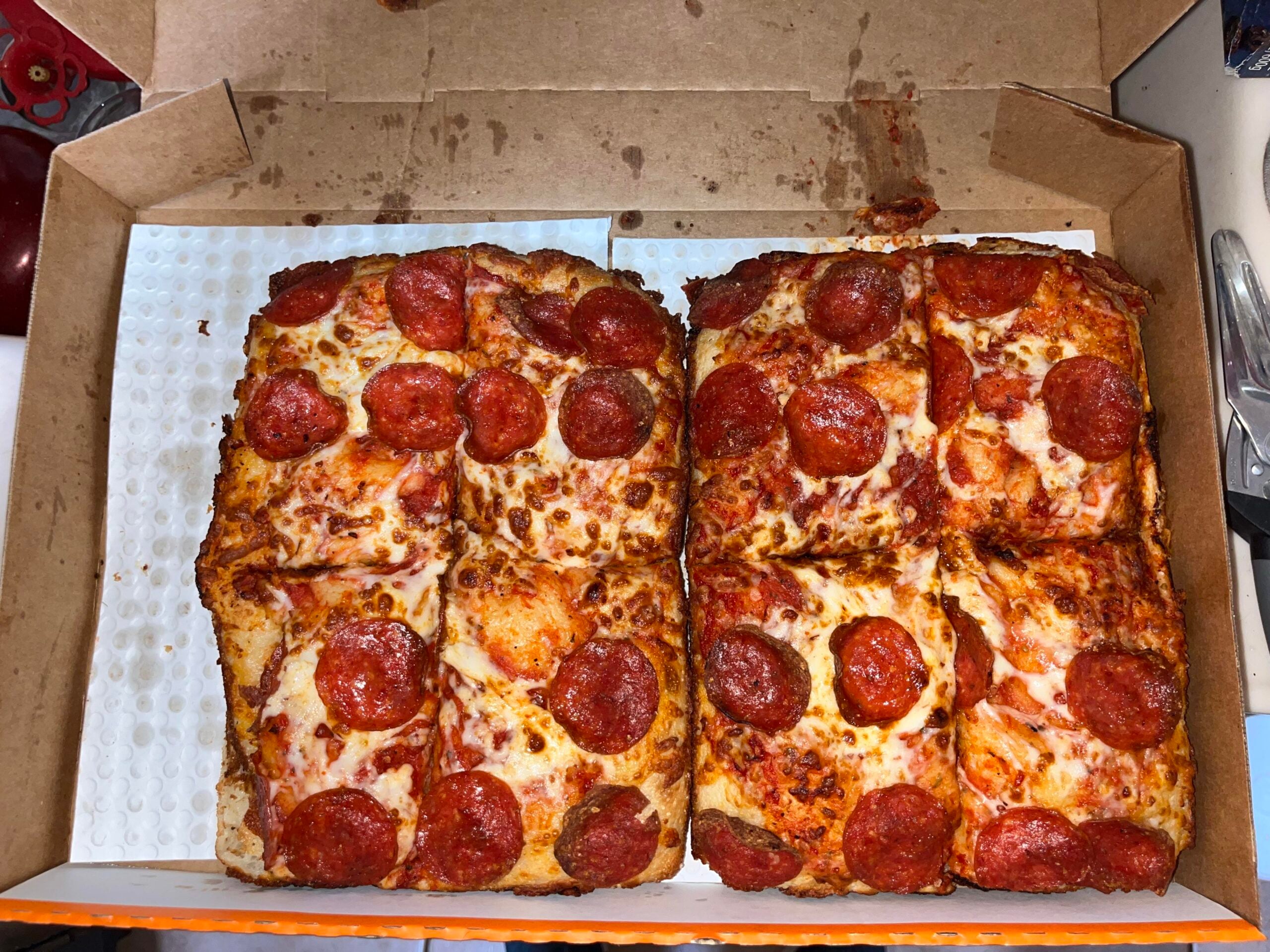 Two square-cut pepperoni pizzas in a cardboard delivery box.