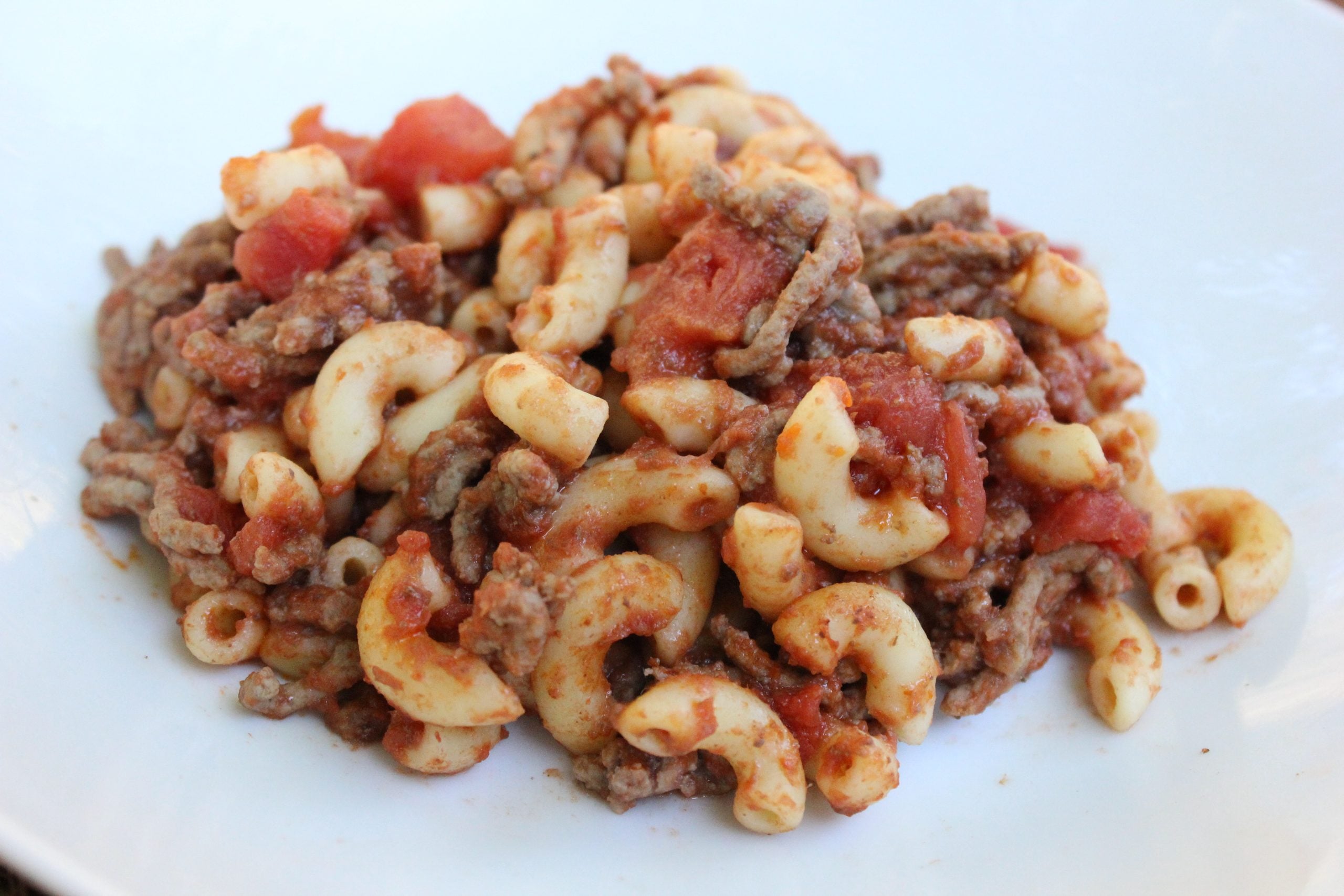 A serving of macaroni pasta mixed with ground meat and tomato sauce.