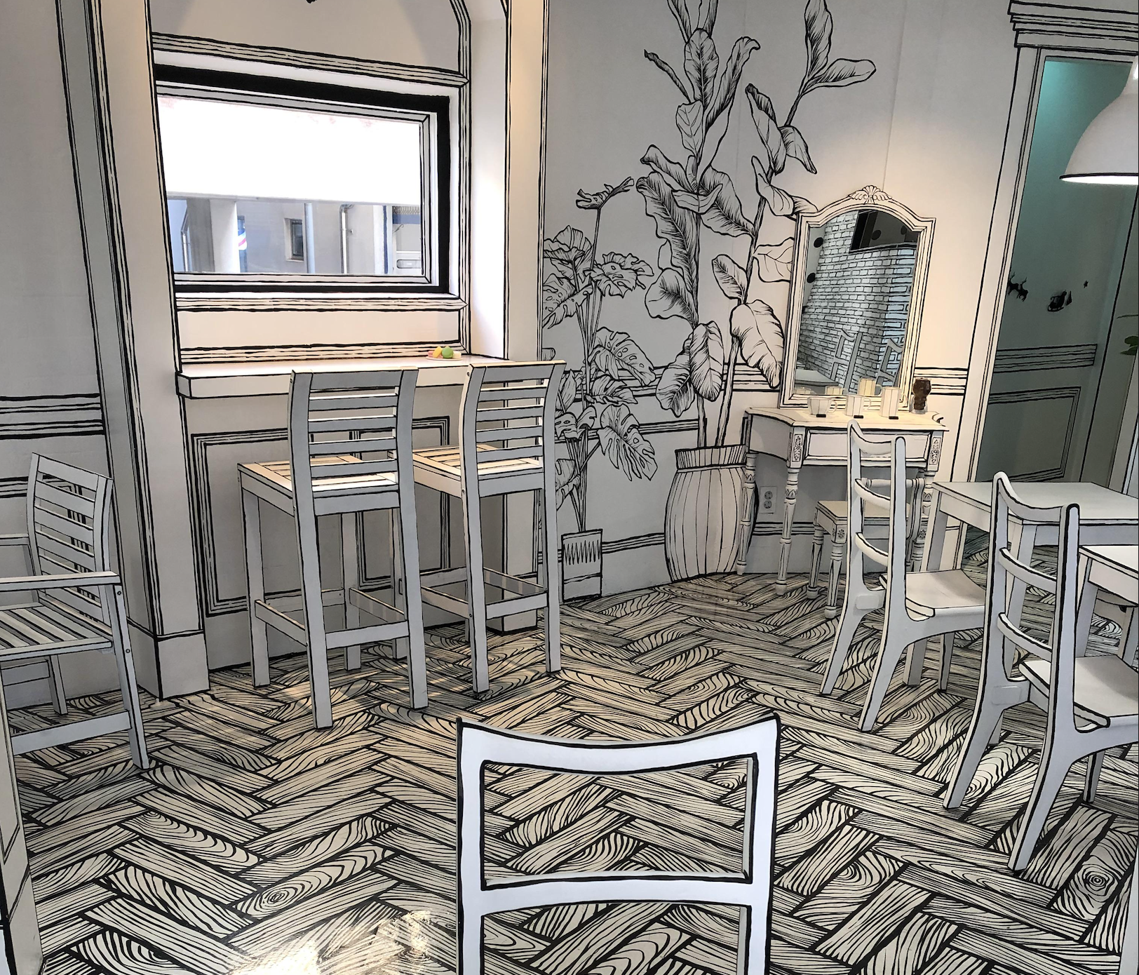 A café interior with furniture and decor painted in black outlines, creating a look that resembles a 2D sketch or cartoon. The floor has a herringbone pattern, and there are plants and a vanity table visible.