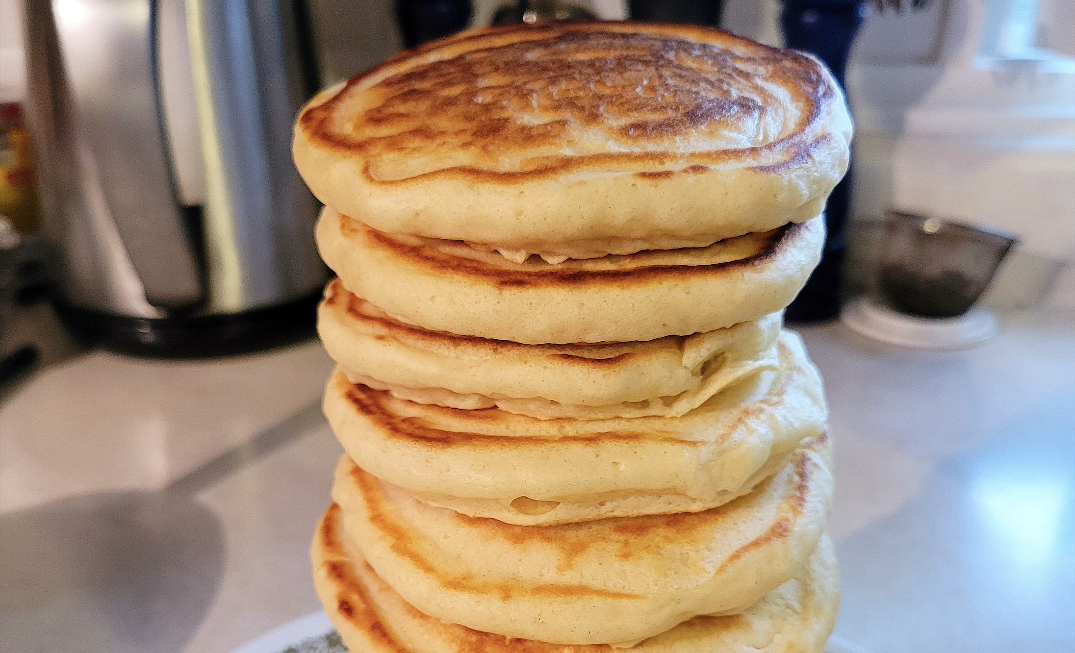 A tall stack of six golden-brown pancakes, with one other those pancake recipes shared.