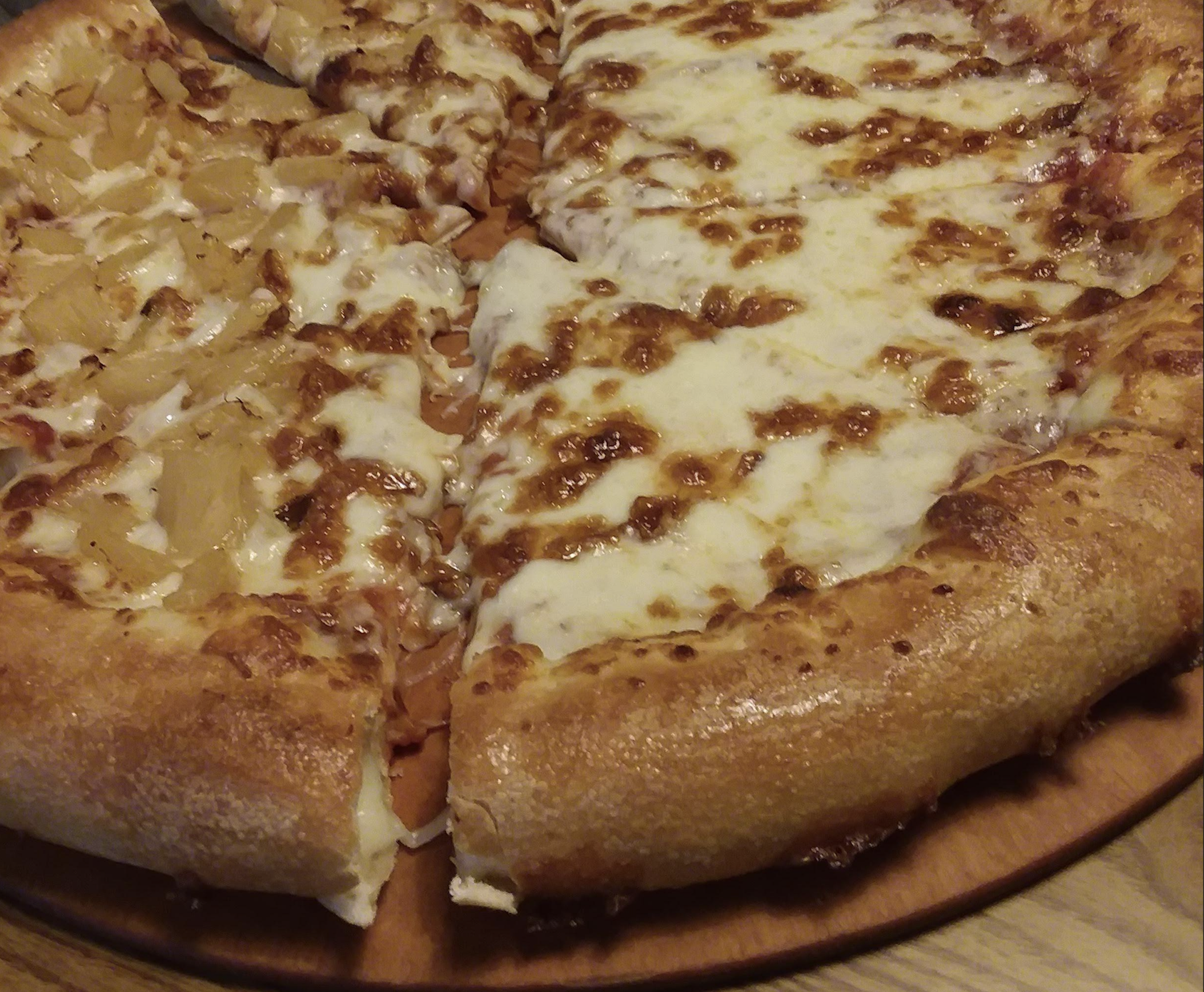 A pizza cut into slices, with half topped with pineapple and the other half topped with melted cheese.