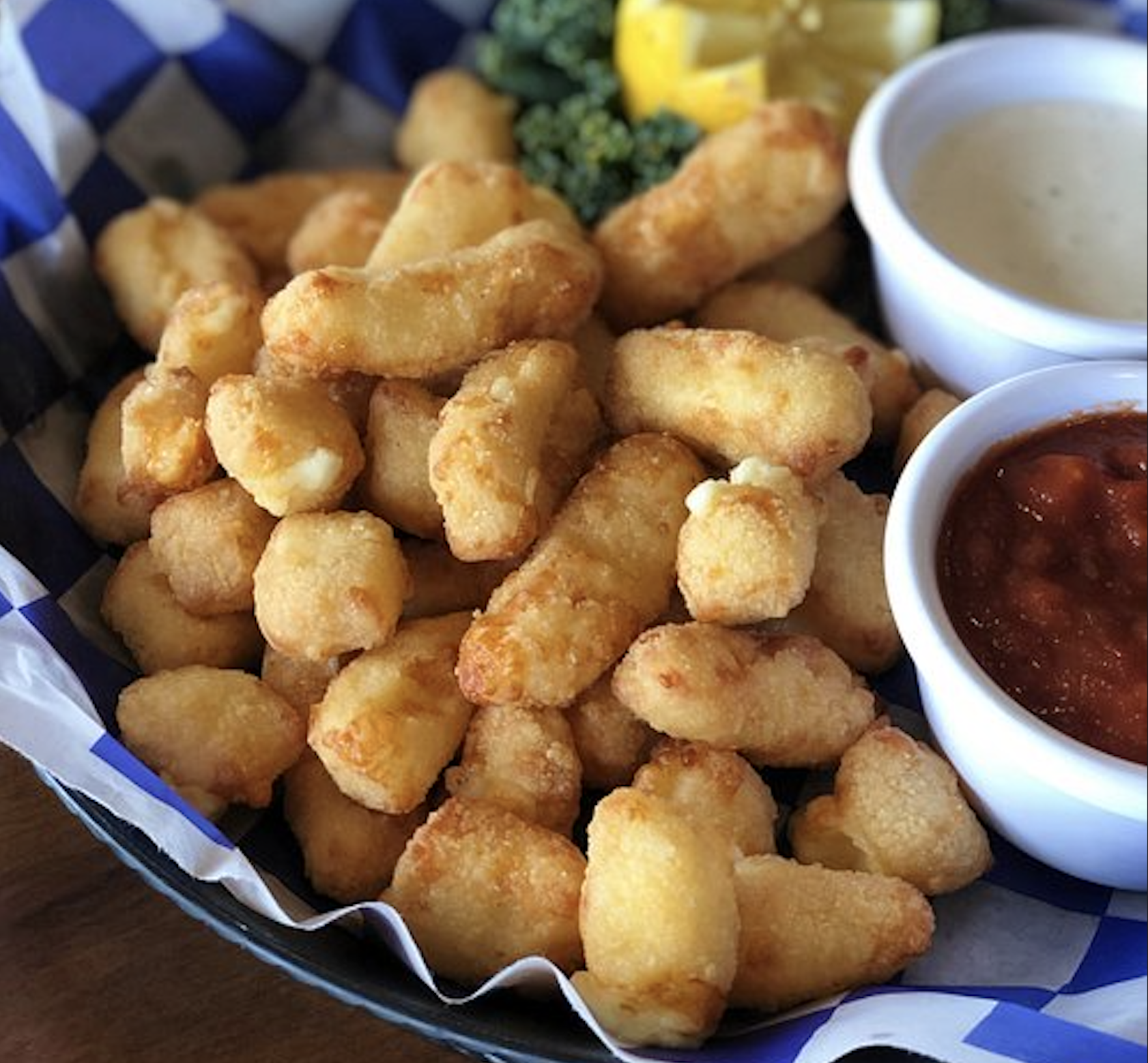 A basket of fried cheese curds served with two dipping sauces.
