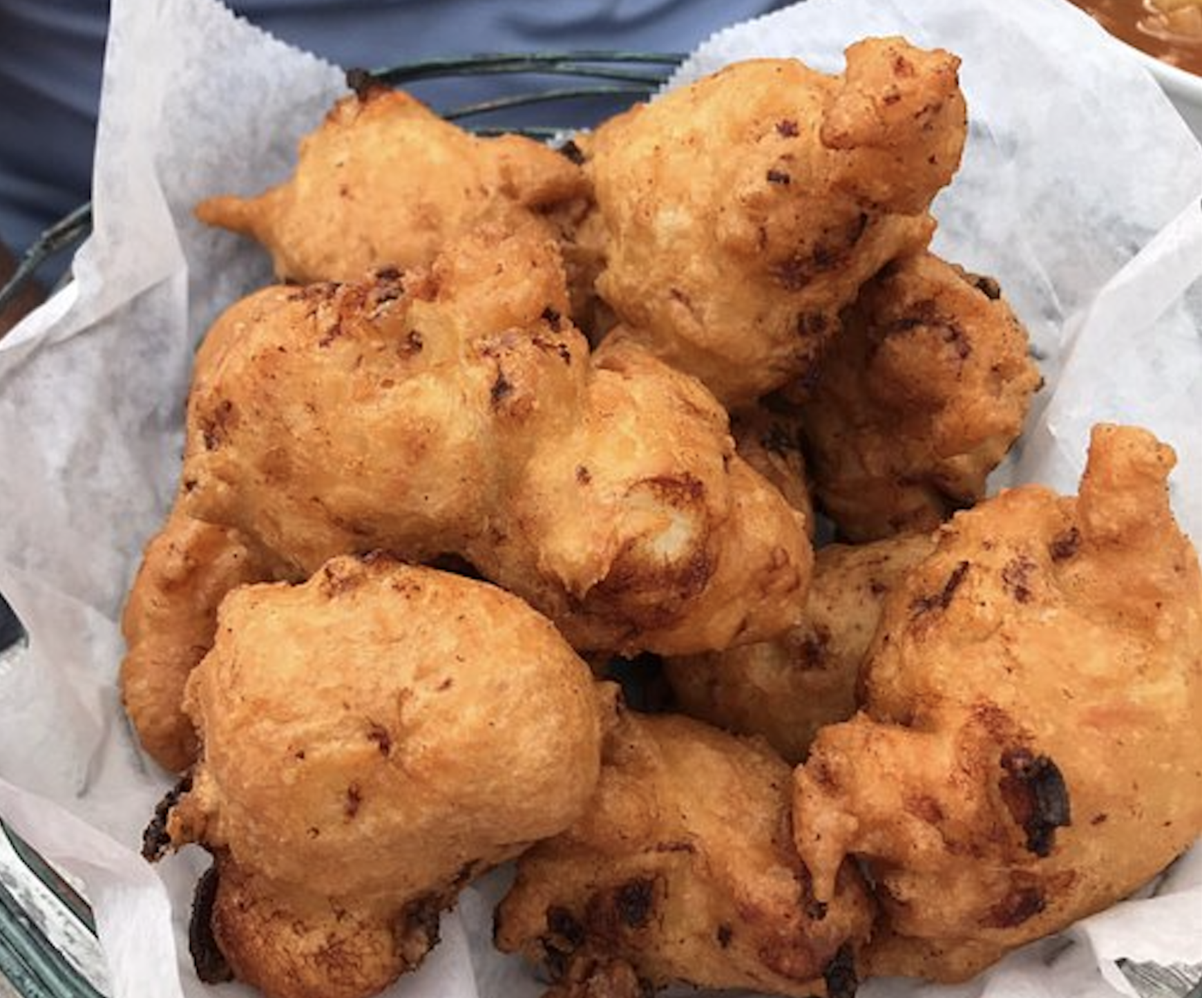 A basket of golden-brown fried hushpuppies served on parchment paper.