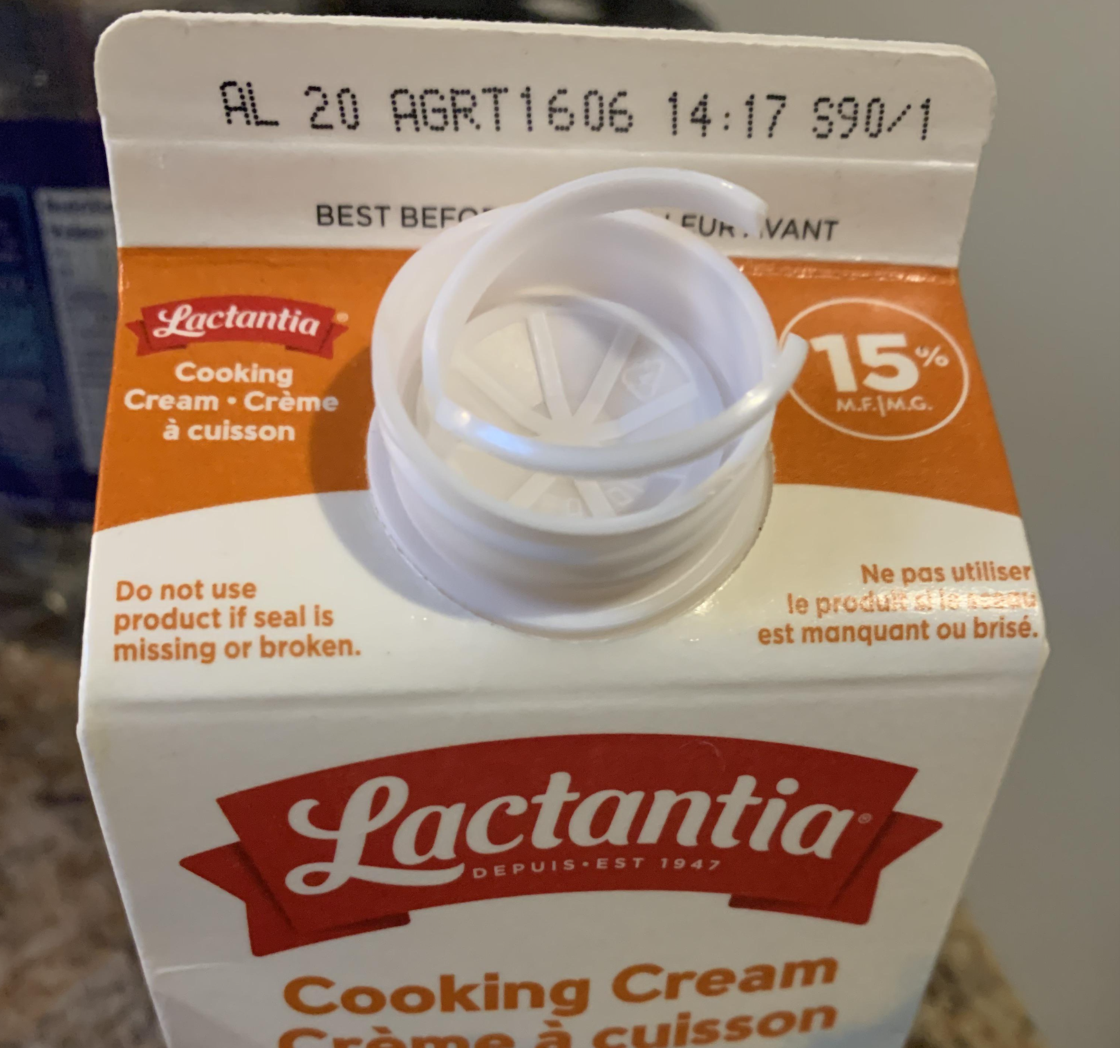 Top of a Lactantia 15% cooking cream carton with an open plastic spout and a best-before date printed at the top.