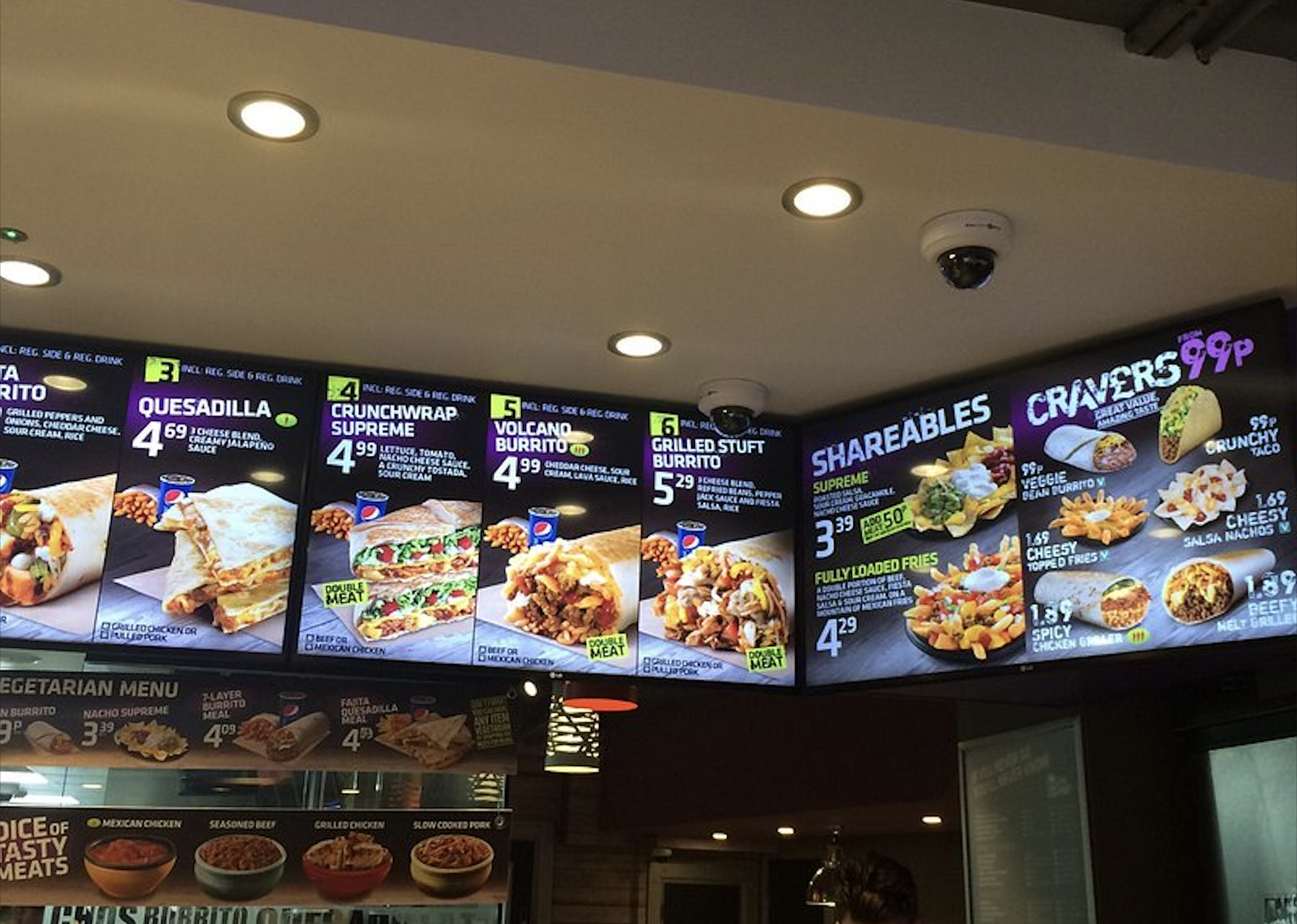 A Taco Bell digital menu board displaying prices and images for various burritos, quesadillas, and shareable items.