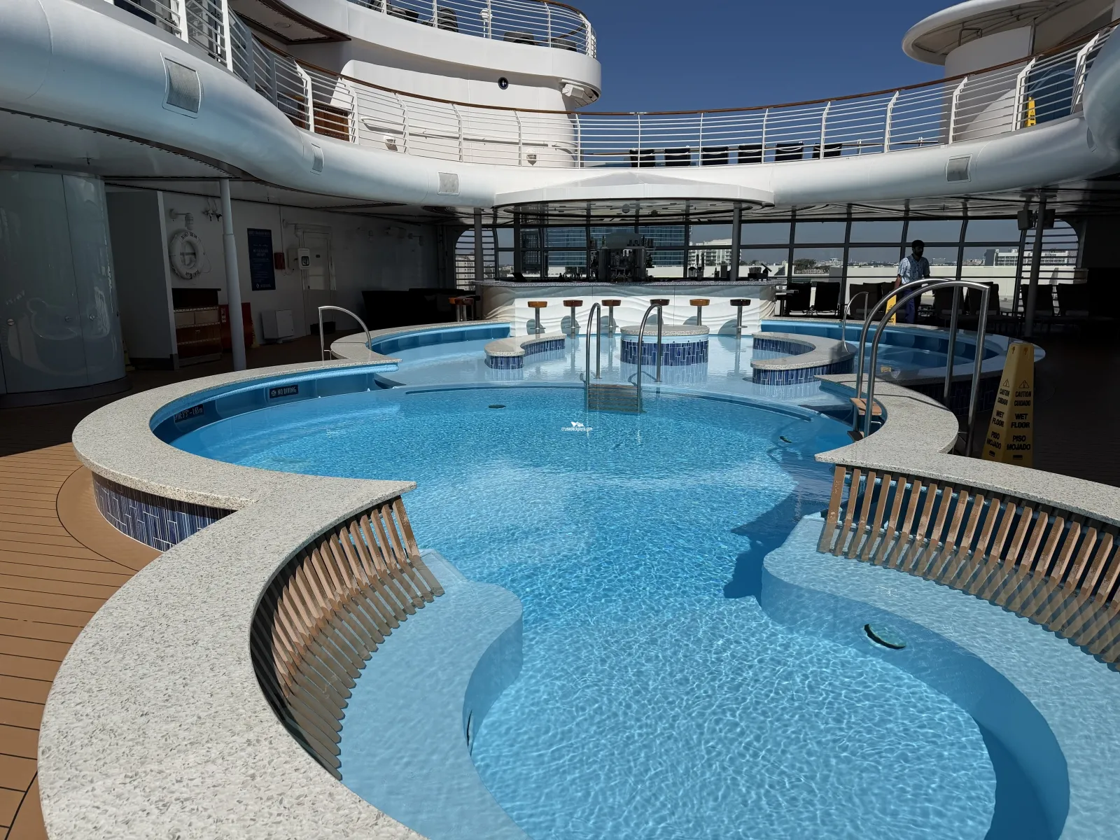 An outdoor cruise ship pool with a swim-up bar and barstools.