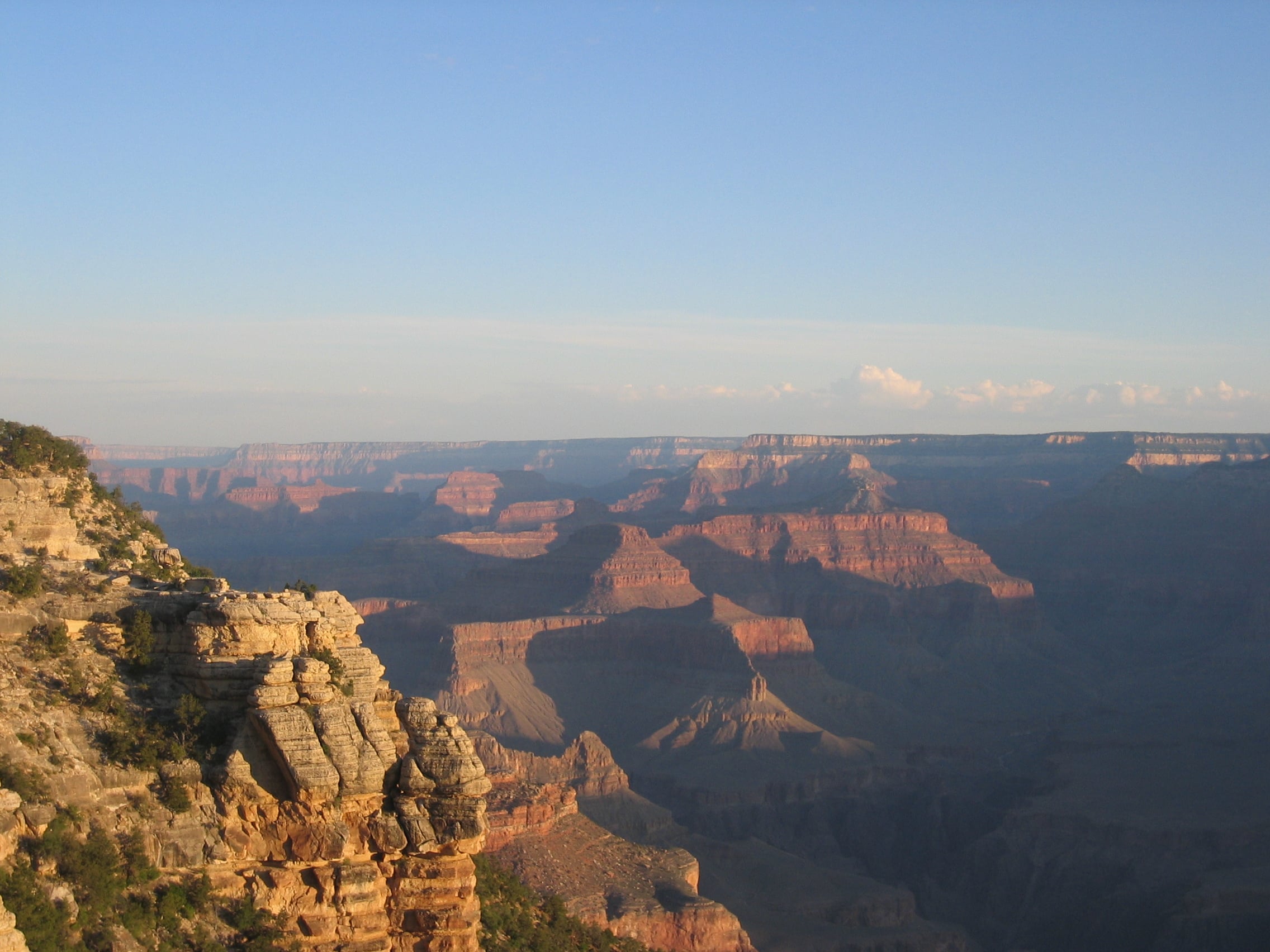 Panoramic view of the Grand Canyon at sunset with deep shadows cast across the rocky layers and plateaus.