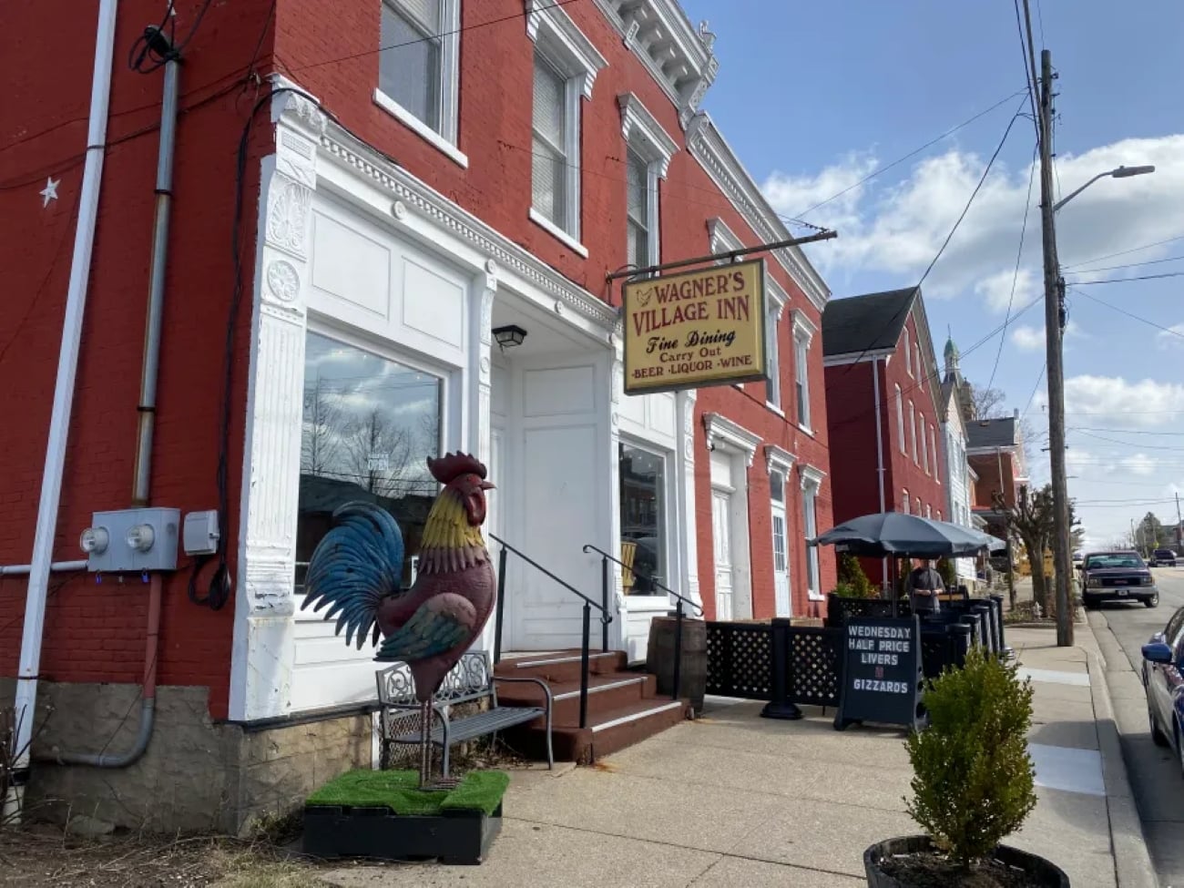 small-town restaurants Wagner’s Village Inn brick building with a large rooster statue out front and a sidewalk sign advertising half-price livers and gizzards.