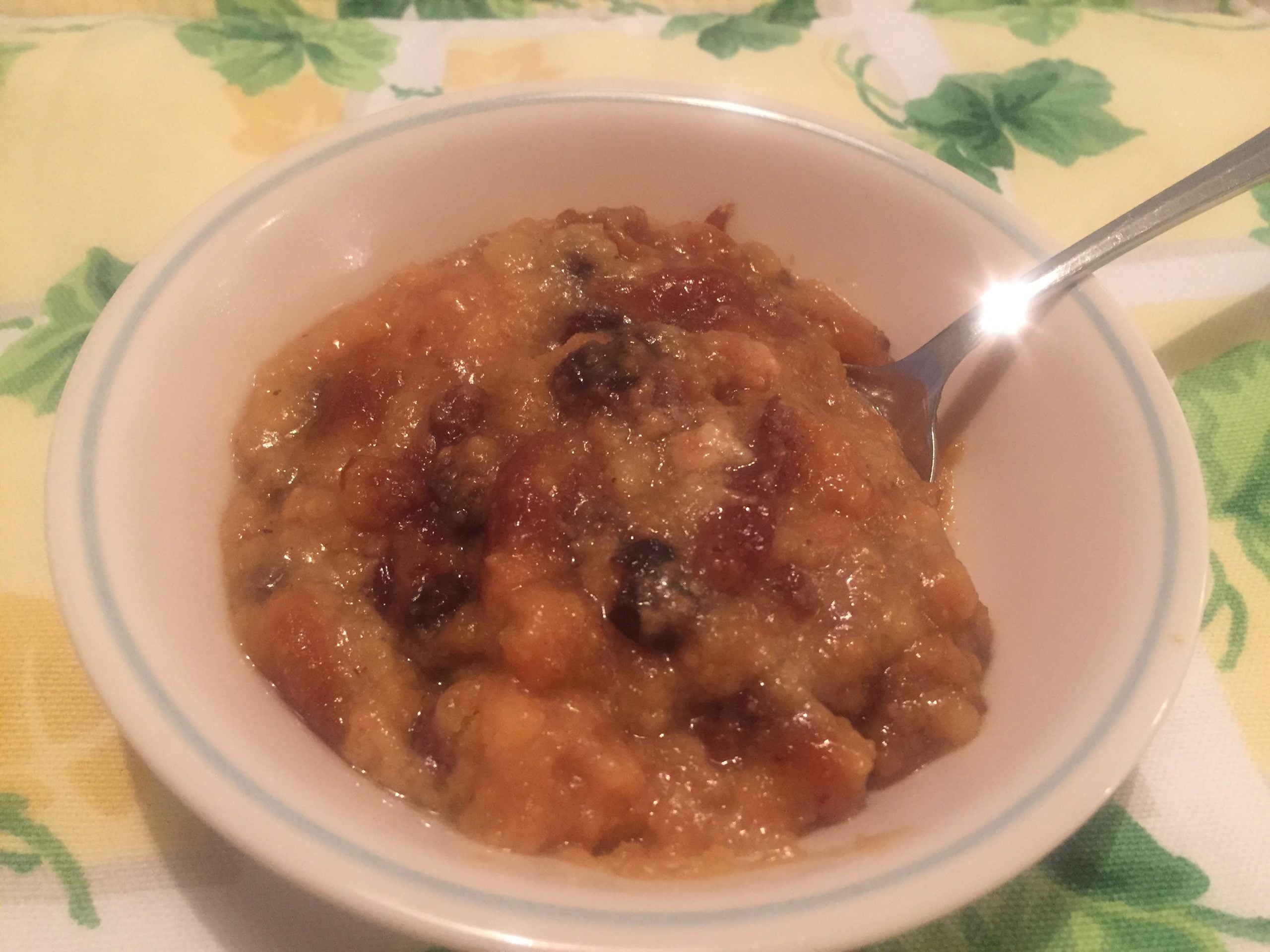 A white bowl filled with regional dessert beans and a metal spoon resting inside.