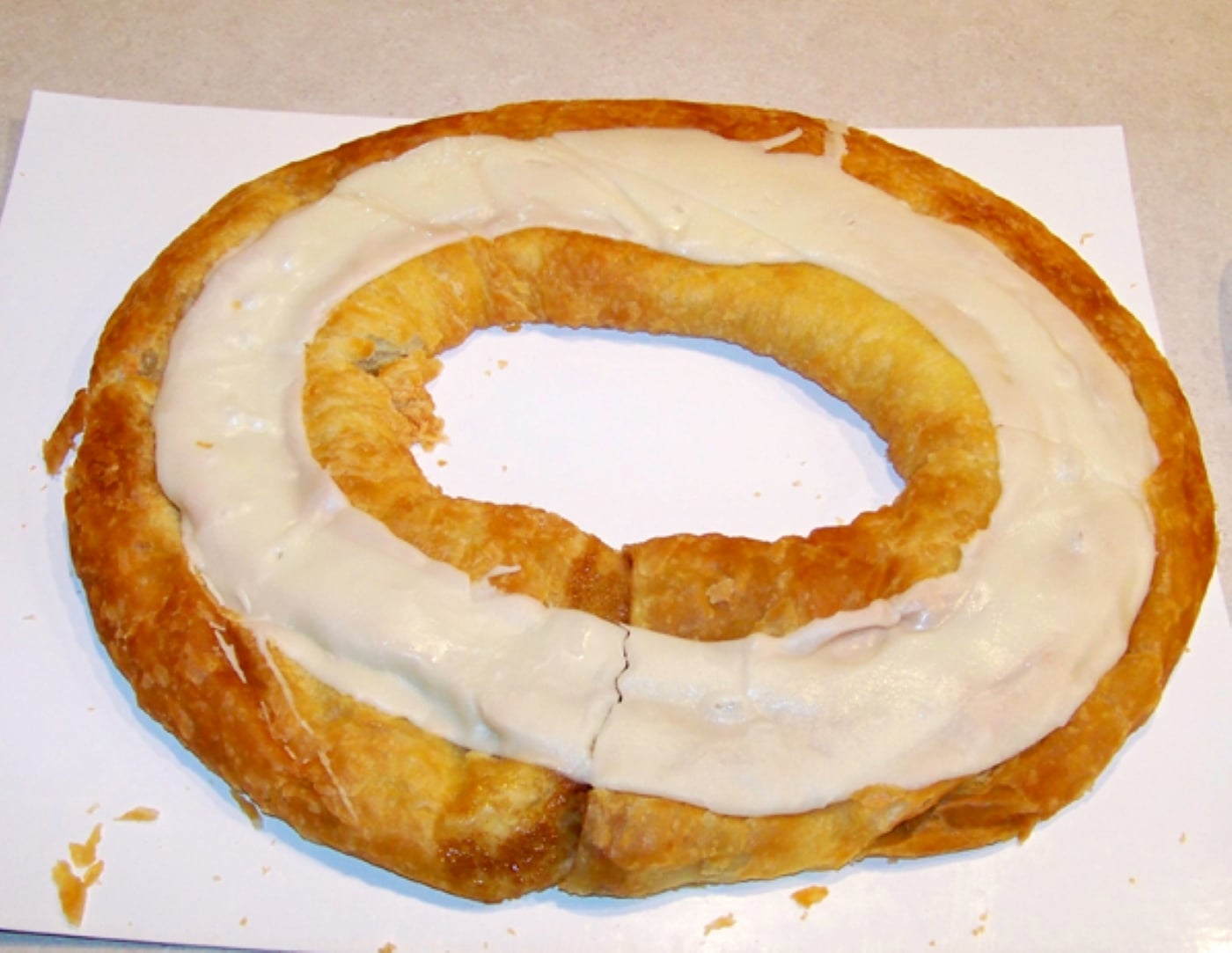 A ring-shaped glazed regional dessert pastry on a white sheet.