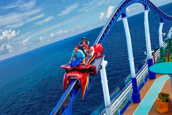 Two people ride the Bolt roller coaster, one of the cruise ship amenities located on the deck above the ocean.