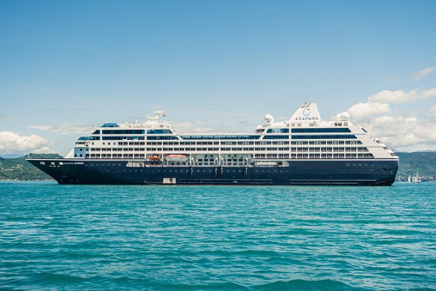 An Azamara cruise ship sailing on blue water, passing by the areas where cruise ship buffets are served.