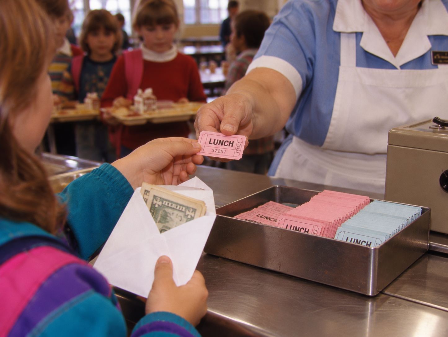 A school cafeteria worker hands a pink lunch ticket to a student holding a white envelope filled with cash.