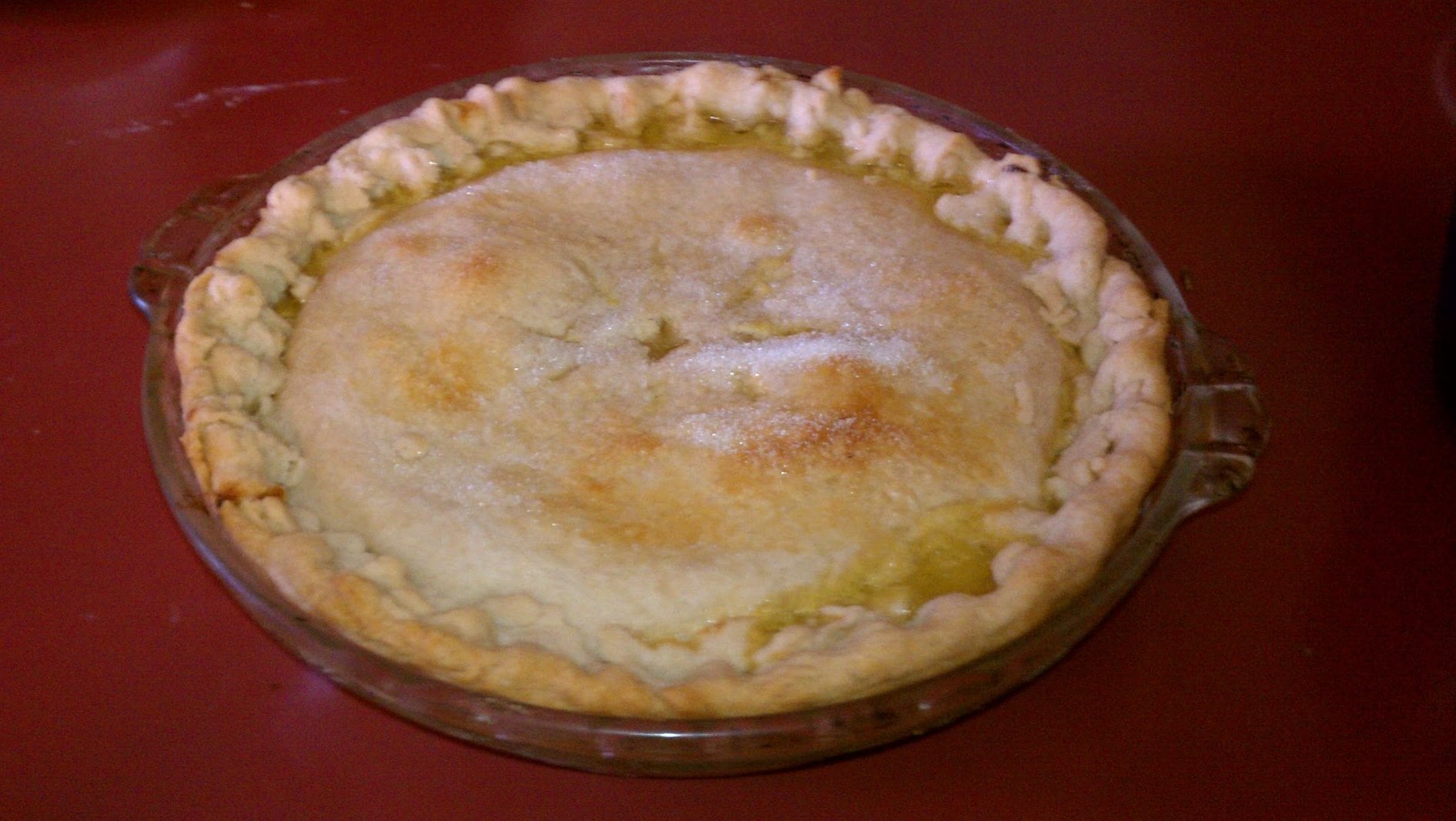 A regional dessert pie in a glass dish with a crimped crust and a sugar-dusted top.