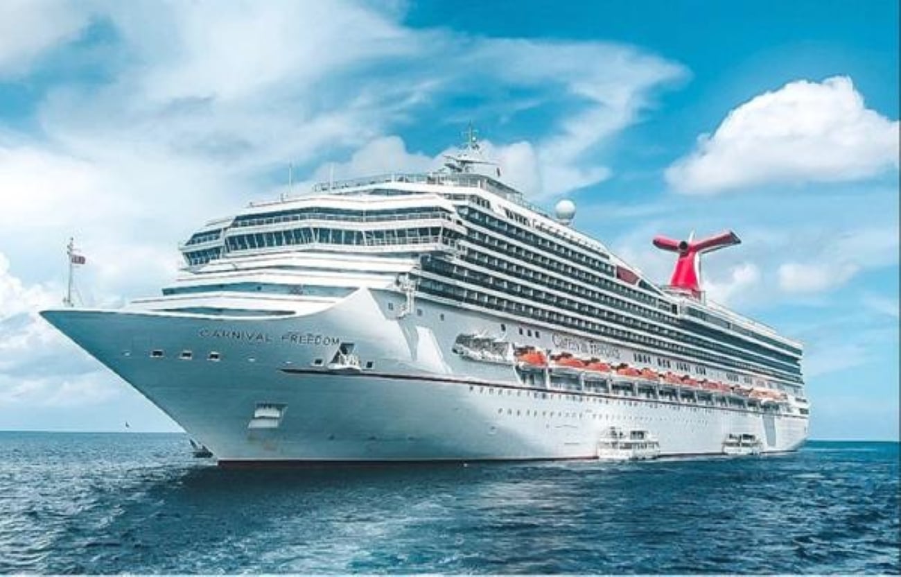 The Carnival Freedom cruise ship sails on the ocean under a blue sky, heading toward destinations known for their extensive cruise ship buffets.