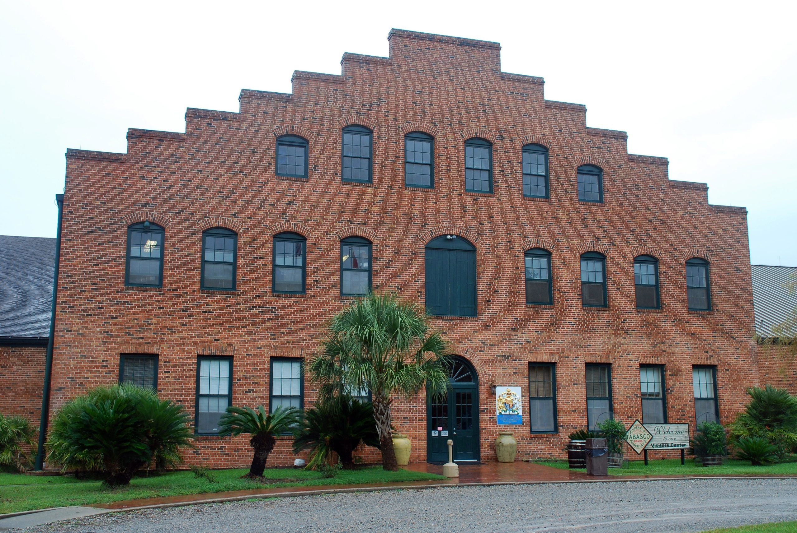 A three-story brick building with a stepped roofline and an entrance featuring a coat of arms and a “Welcome to the Tabasco Visitors Center” sign, a popular stop for food trips.