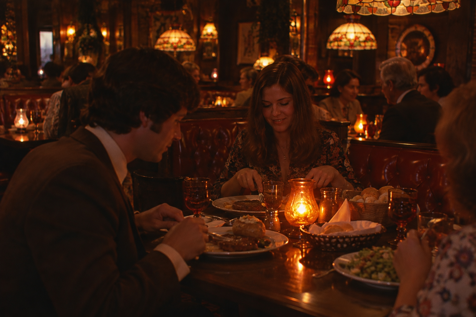 A man and a woman sit at a dimly lit restaurant table, enjoying dinner. Warm lighting, red leather booths, and stained-glass lamps create a cozy, intimate atmosphere. Other diners are visible in the background.