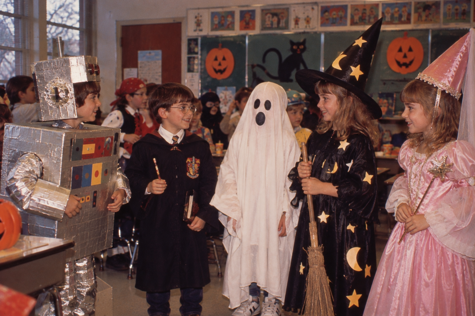 Children in costumes of a robot, a wizard, a ghost, a witch, and a fairy standing in a decorated classroom.