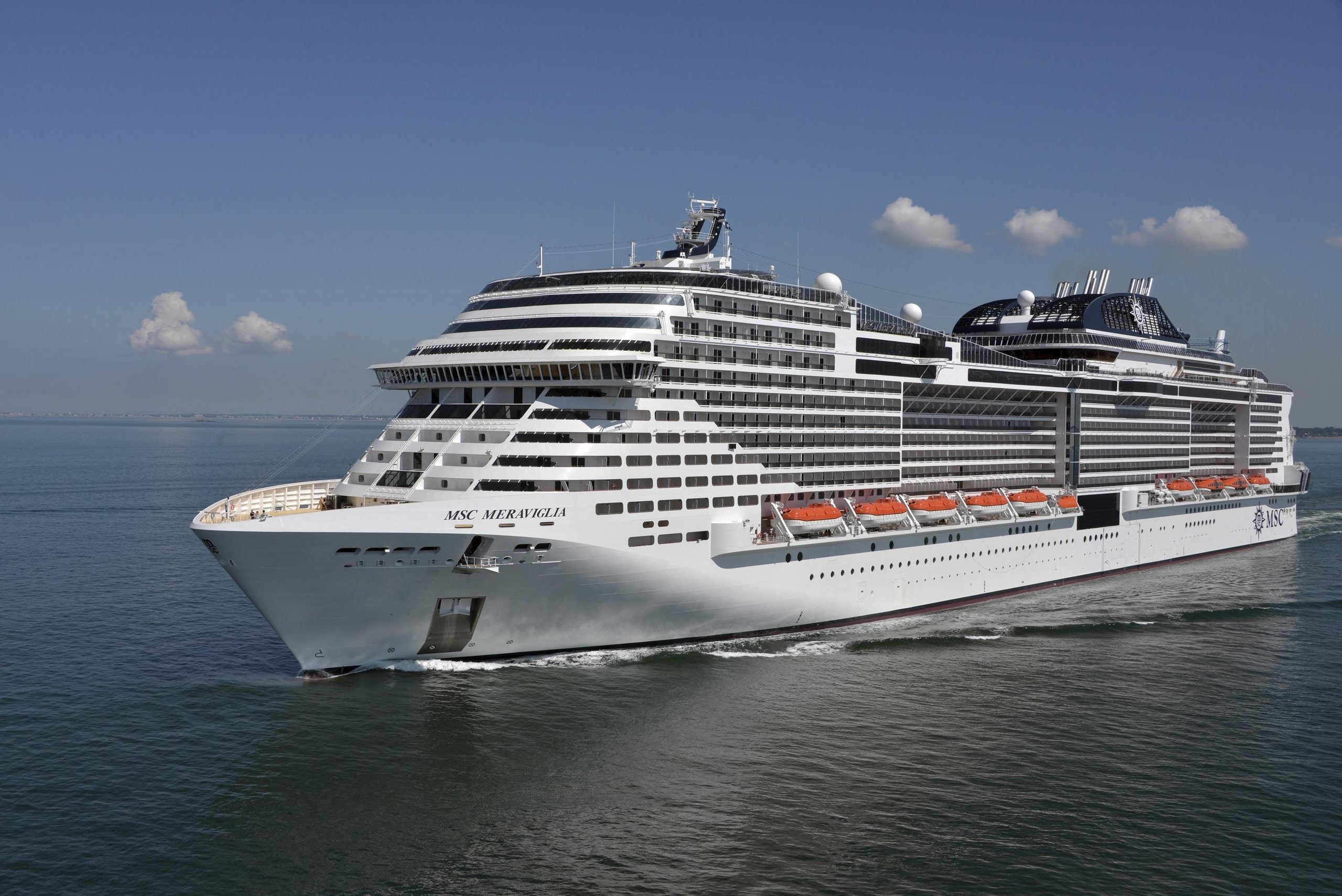 The MSC Meraviglia cruise ship sails on the ocean under a clear blue sky, often a popular choice for travelers seeking extensive cruise ship buffets.