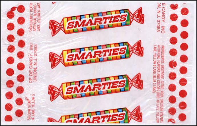 Clear plastic wrapper featuring four Smarties candy rolls printed in a vertical row, bordered by columns of red dots.