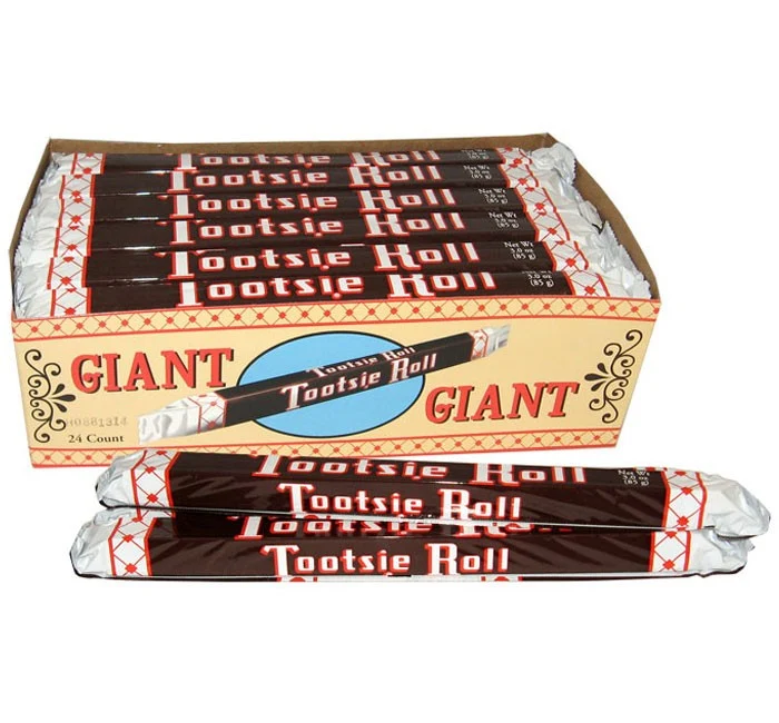 A display box of 24 Giant Tootsie Rolls with two additional wrapped candies resting in front.