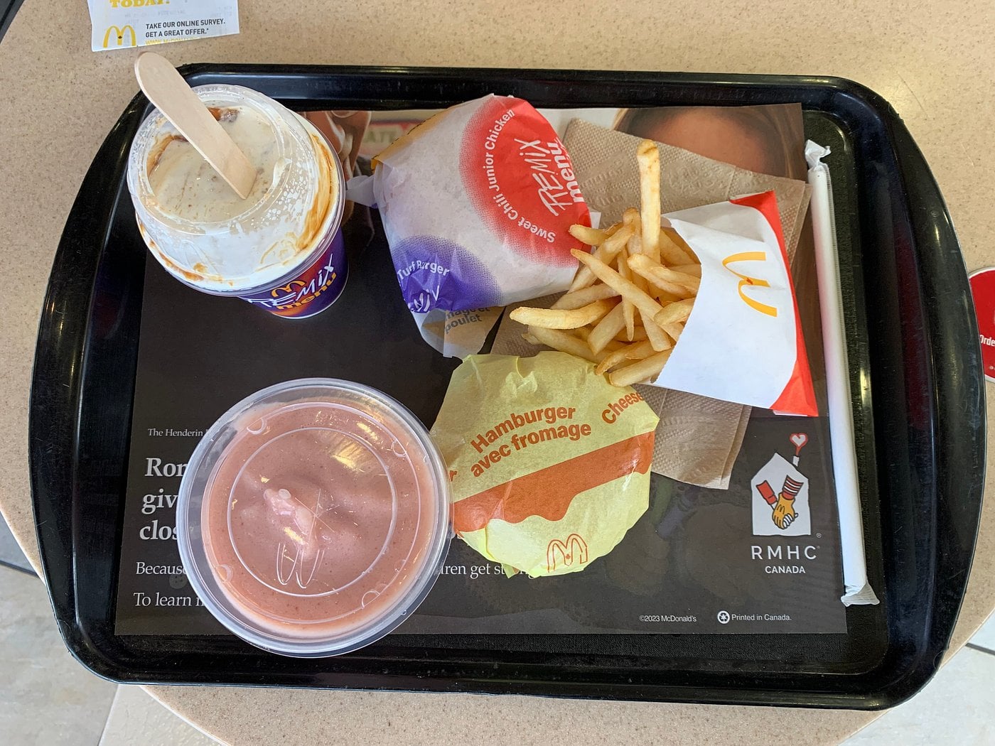 McDonald’s tray containing a Sweet Chili Junior Chicken, a cheeseburger, a small order of fries, a McFlurry with a wooden spoon, and a smoothie.