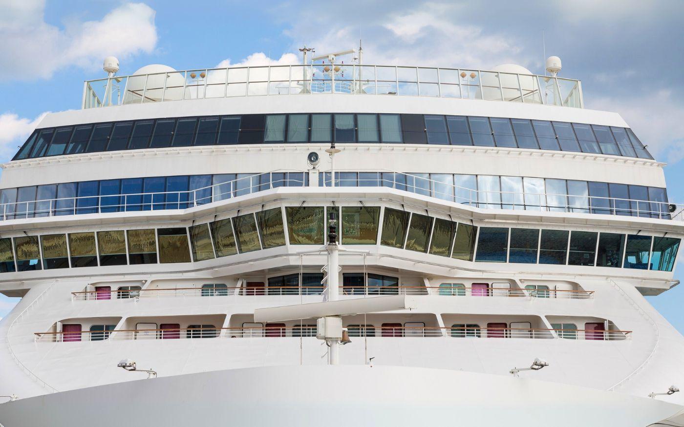 The bridge and upper decks of a large white cruise ship viewed from the front.