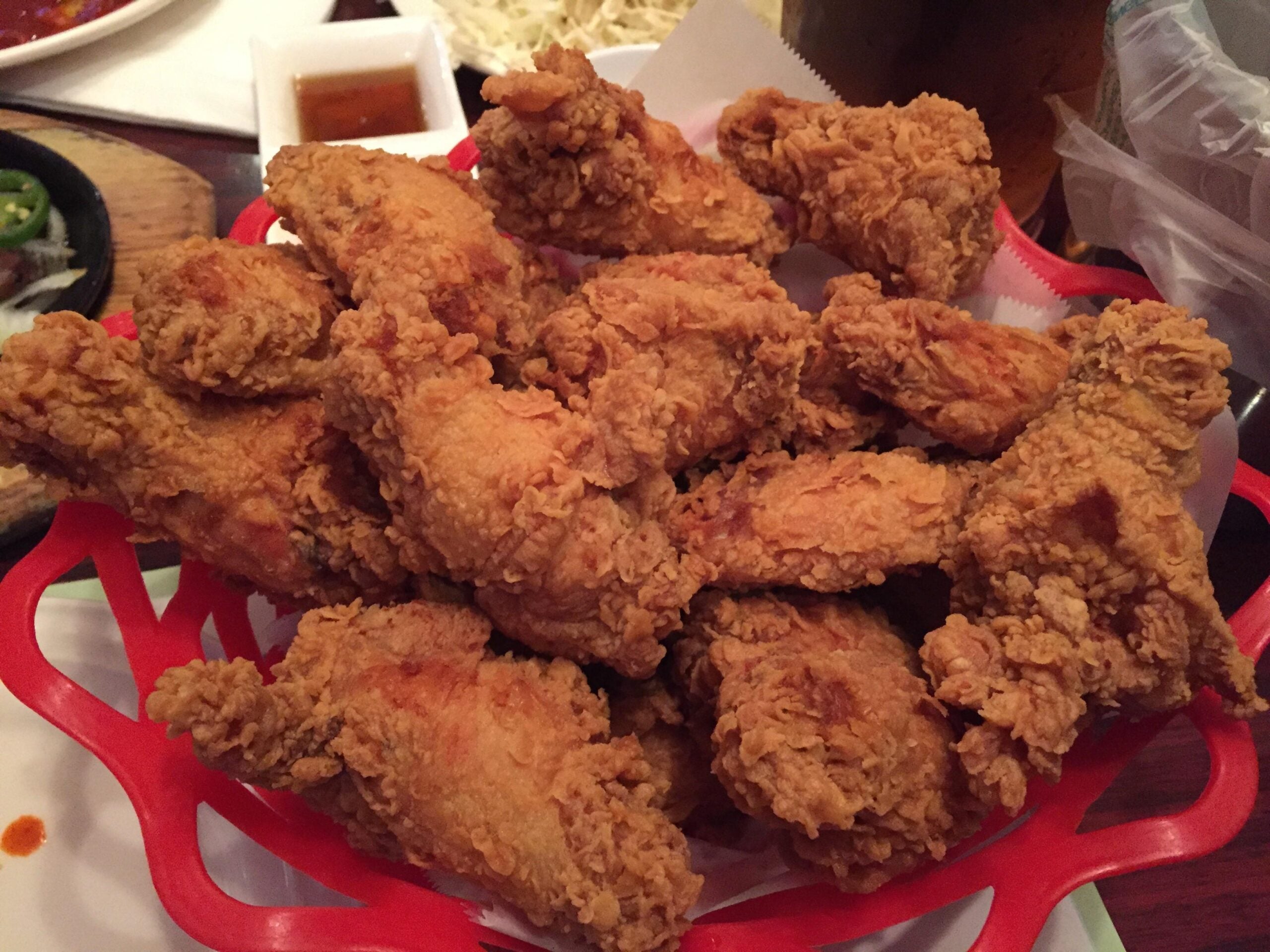 A red plastic basket filled with breaded, fried chicken pieces.