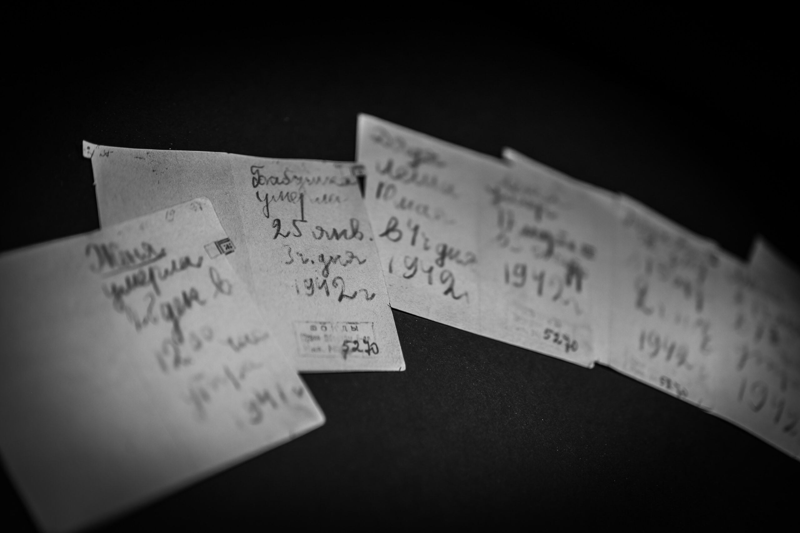 Several handwritten notes in Russian documenting dates of death, dated 1942, arranged on a dark surface.