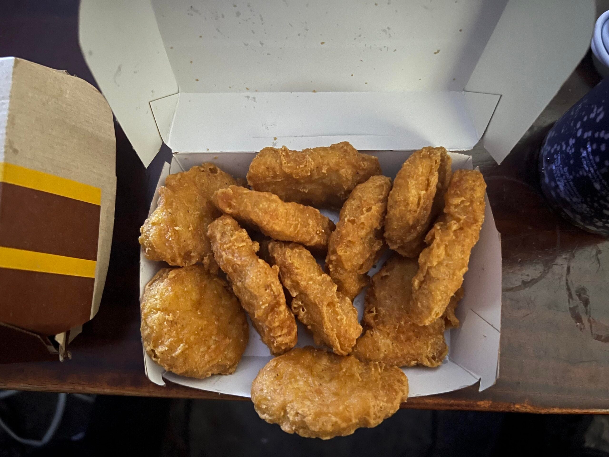 A paper takeout box filled with golden-brown chicken nuggets.